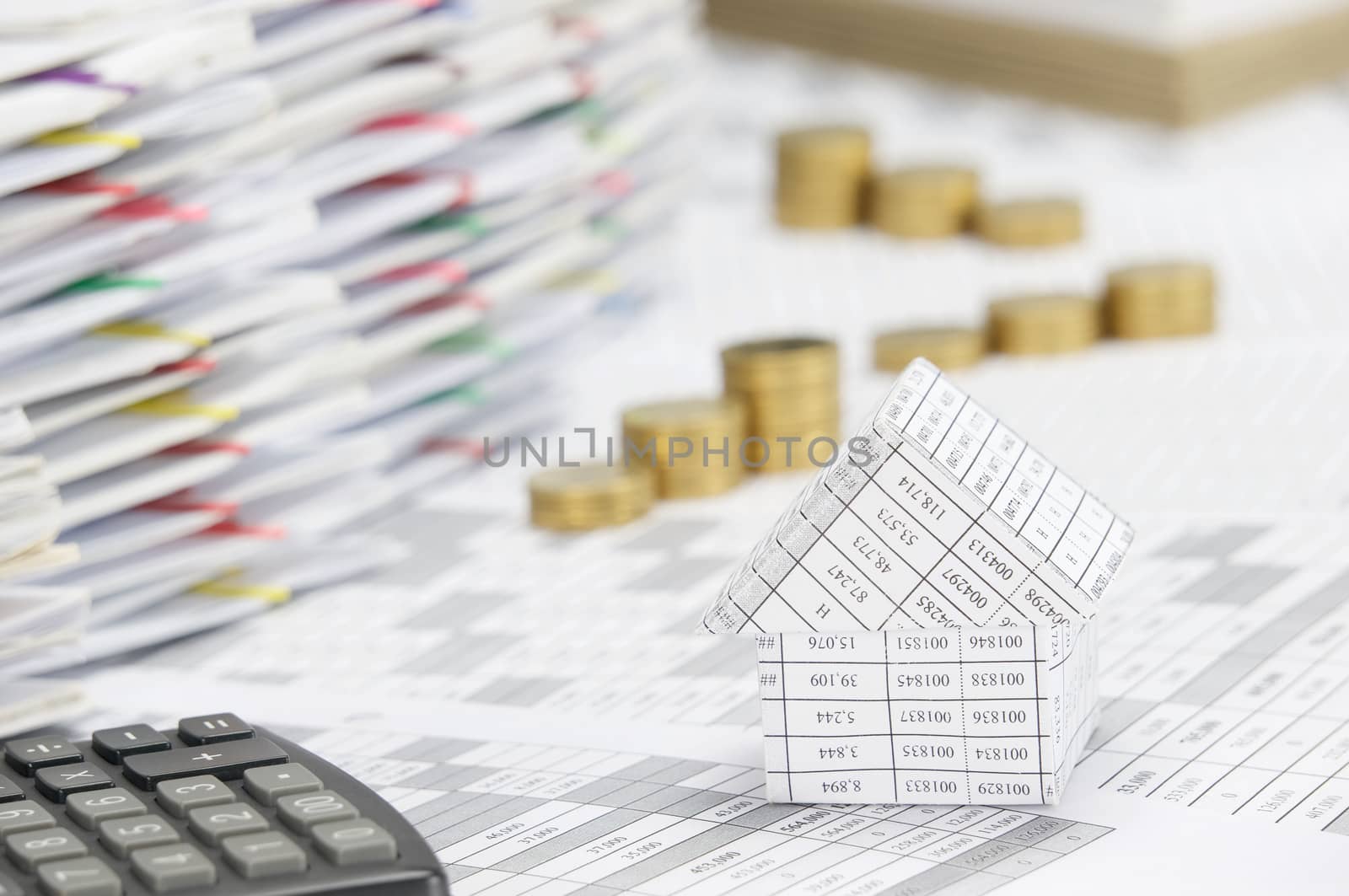 Close up house on finance account have blur step pile of gold coins and pile of document with colorful paperclip and brown envelope as background.