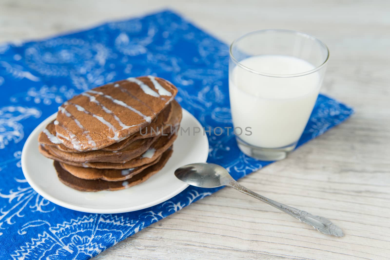 Chocolate pancakes with the glass of milk on the blue napkin