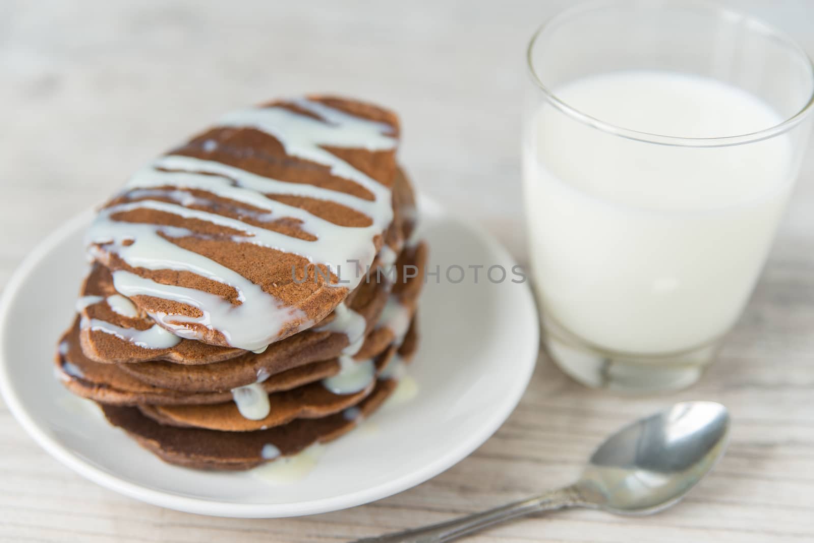 Chocolate pancakes with the glass of milk on the wooden table