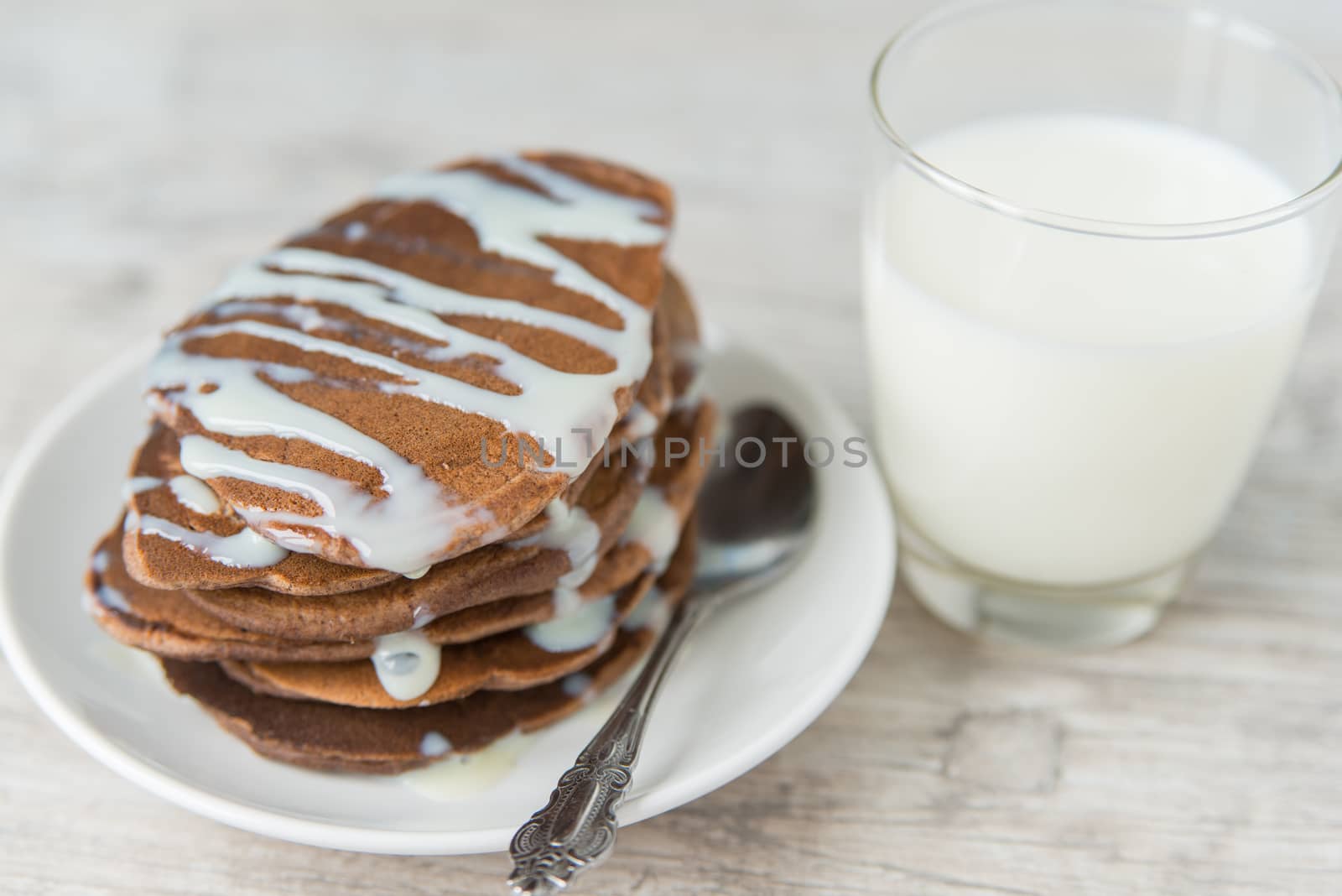 Chocolate pancakes with the glass of milk on the wooden table