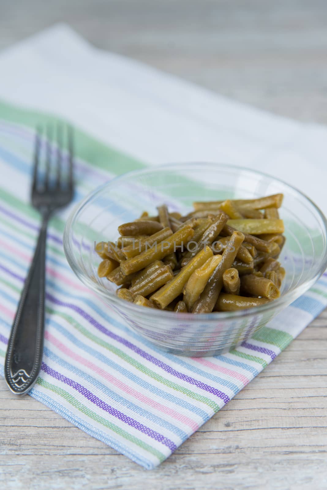 Plate of the prepared green beans and fork on the napkin