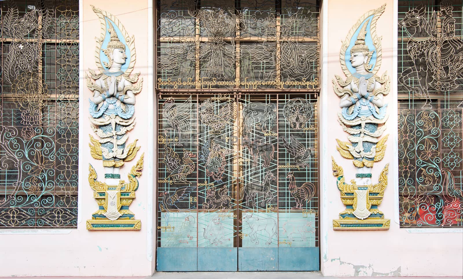 Forged iron door at a temple building at a monastery in Myeik, Tanintharyi Region, South Myanmar, with illustrations from Buddhist history and Asian mythology.