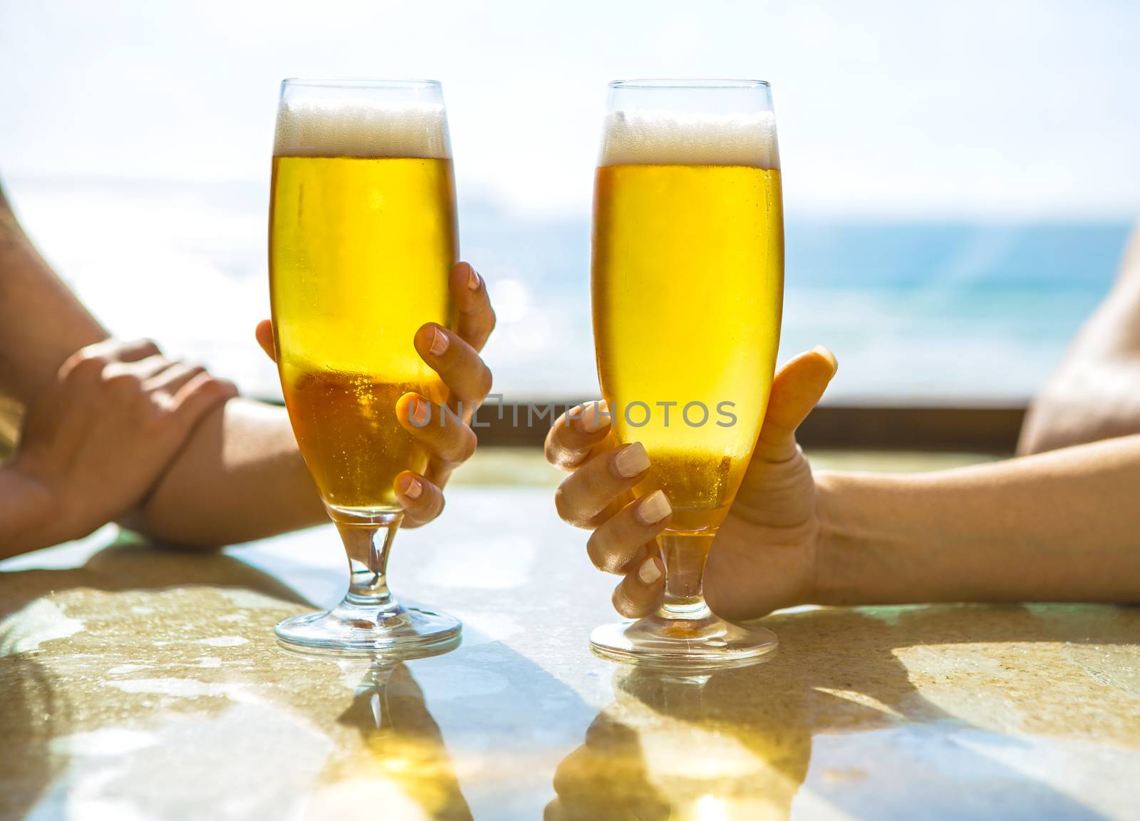 Friends having fun and drinking a cold beer at the beach bar