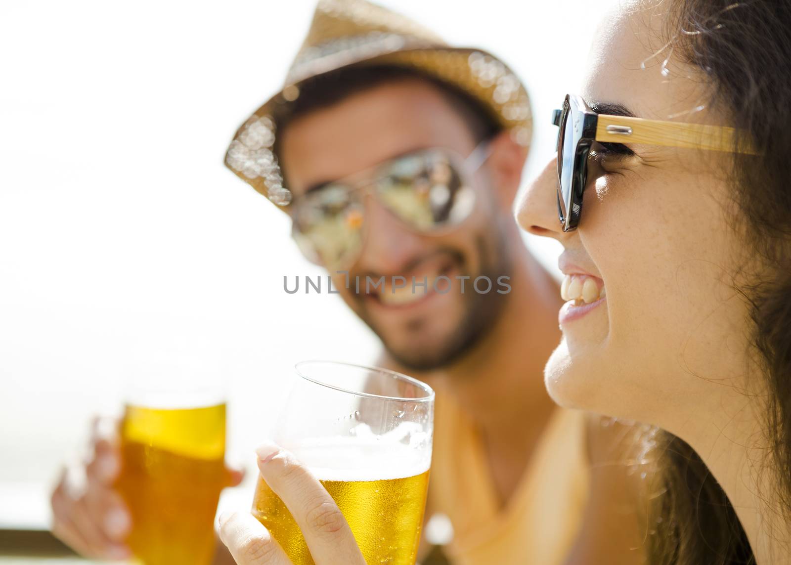 Friends having fun and drinking a cold beer at the beach bar