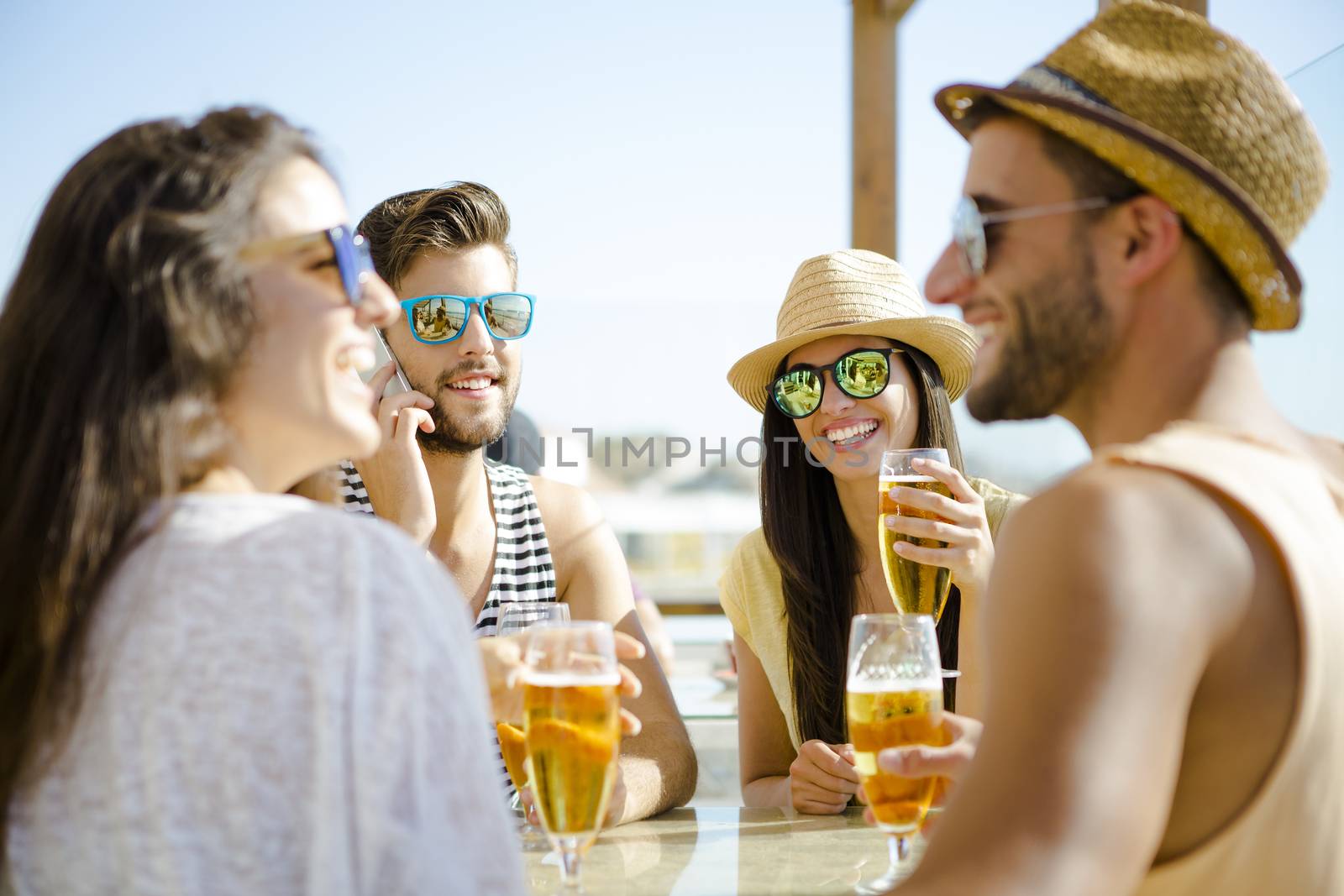 Friends having fun and drinking a cold beer at the beach bar