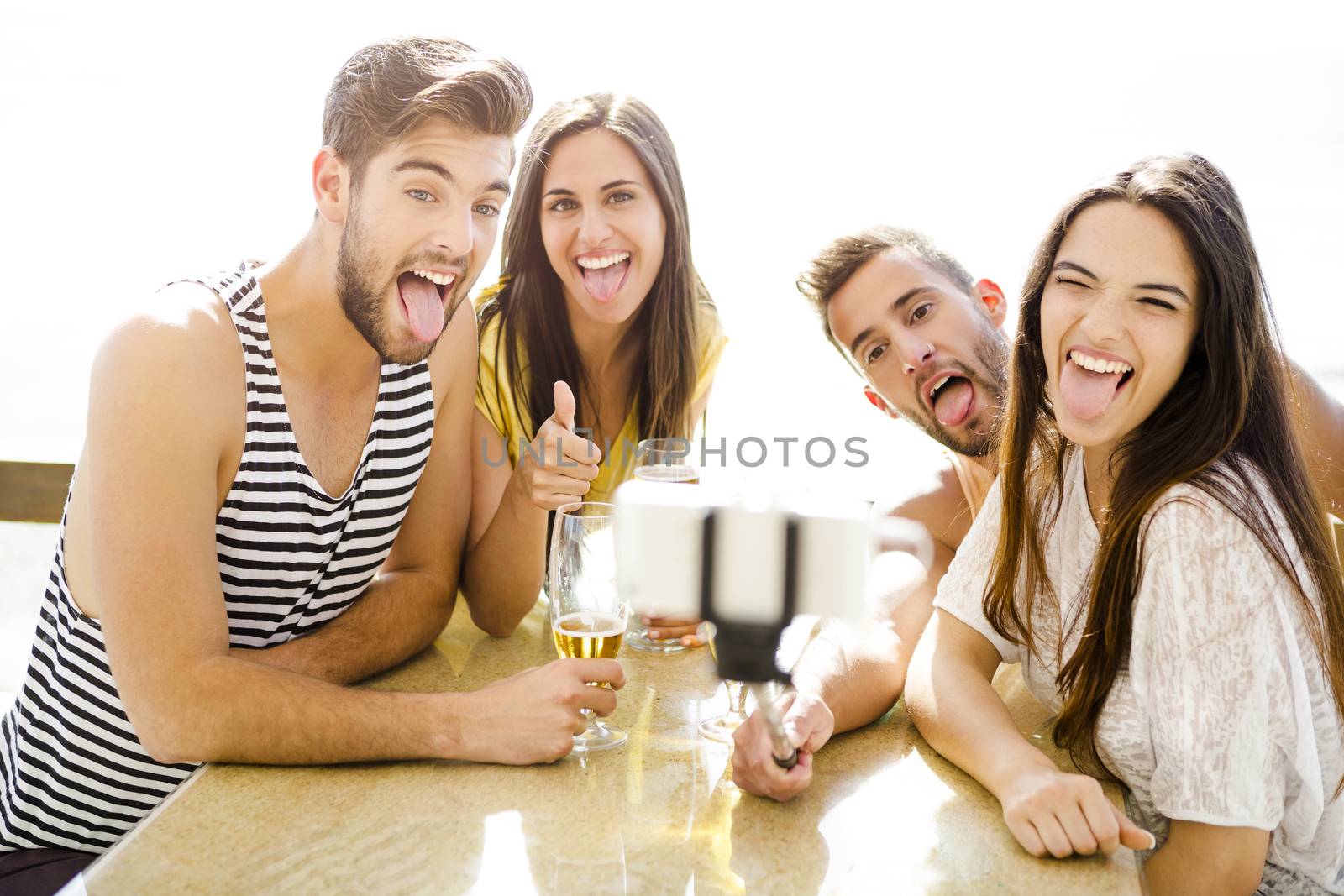 Group of friends at the beach bar and making a selfie