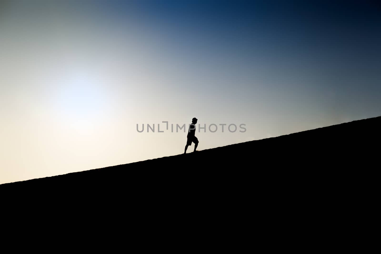 Silhouette of a man climbing a hill by fisfra