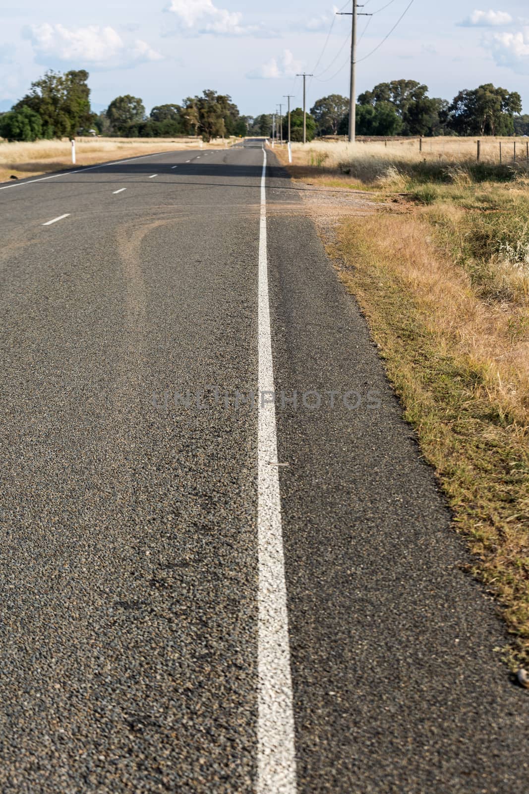 White lines along a road through dried crops in Australia.