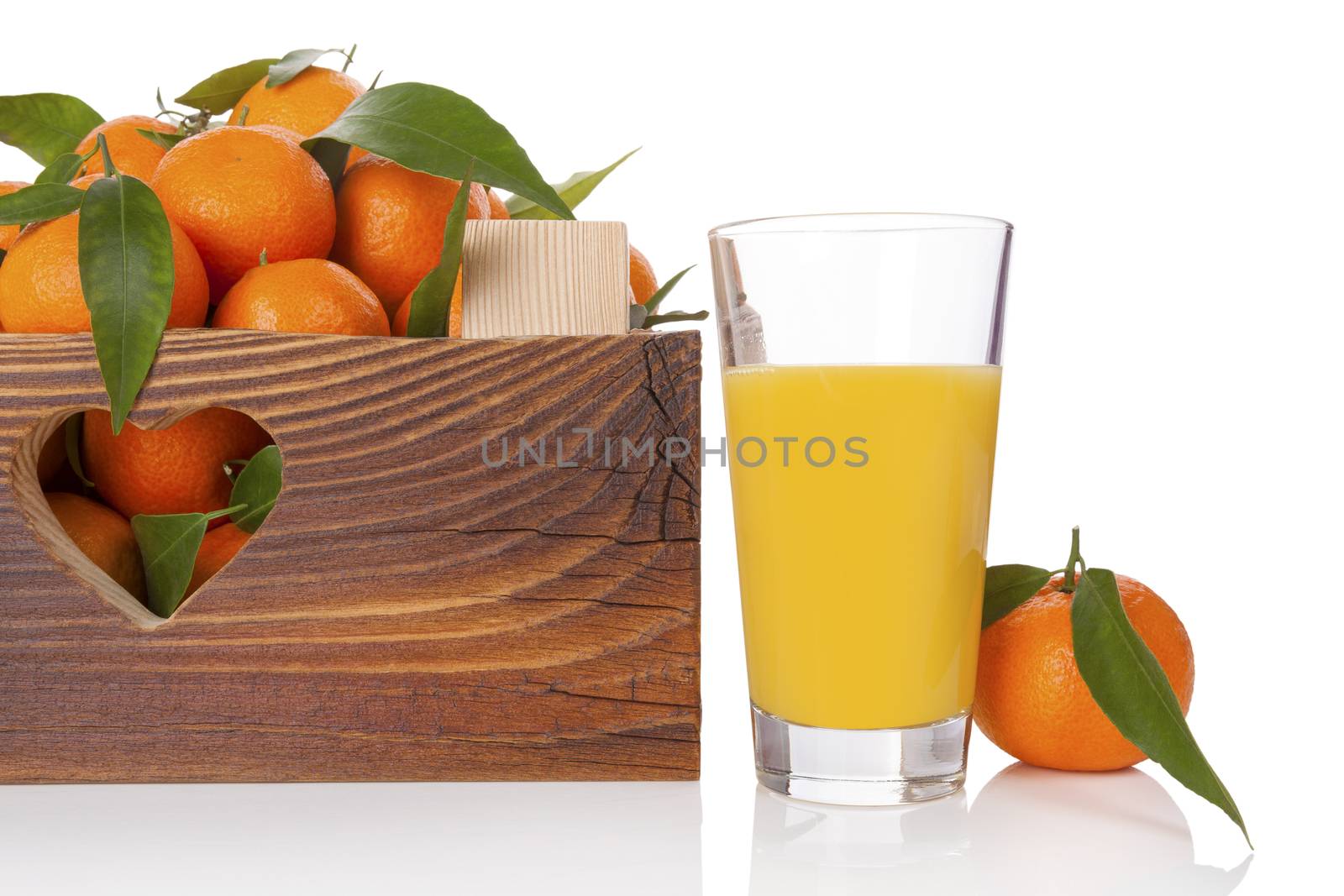 Fresh juice and ripe mandarines with green leaves in wooden crate. Organic fresh mandarines, healthy fruit eating. 