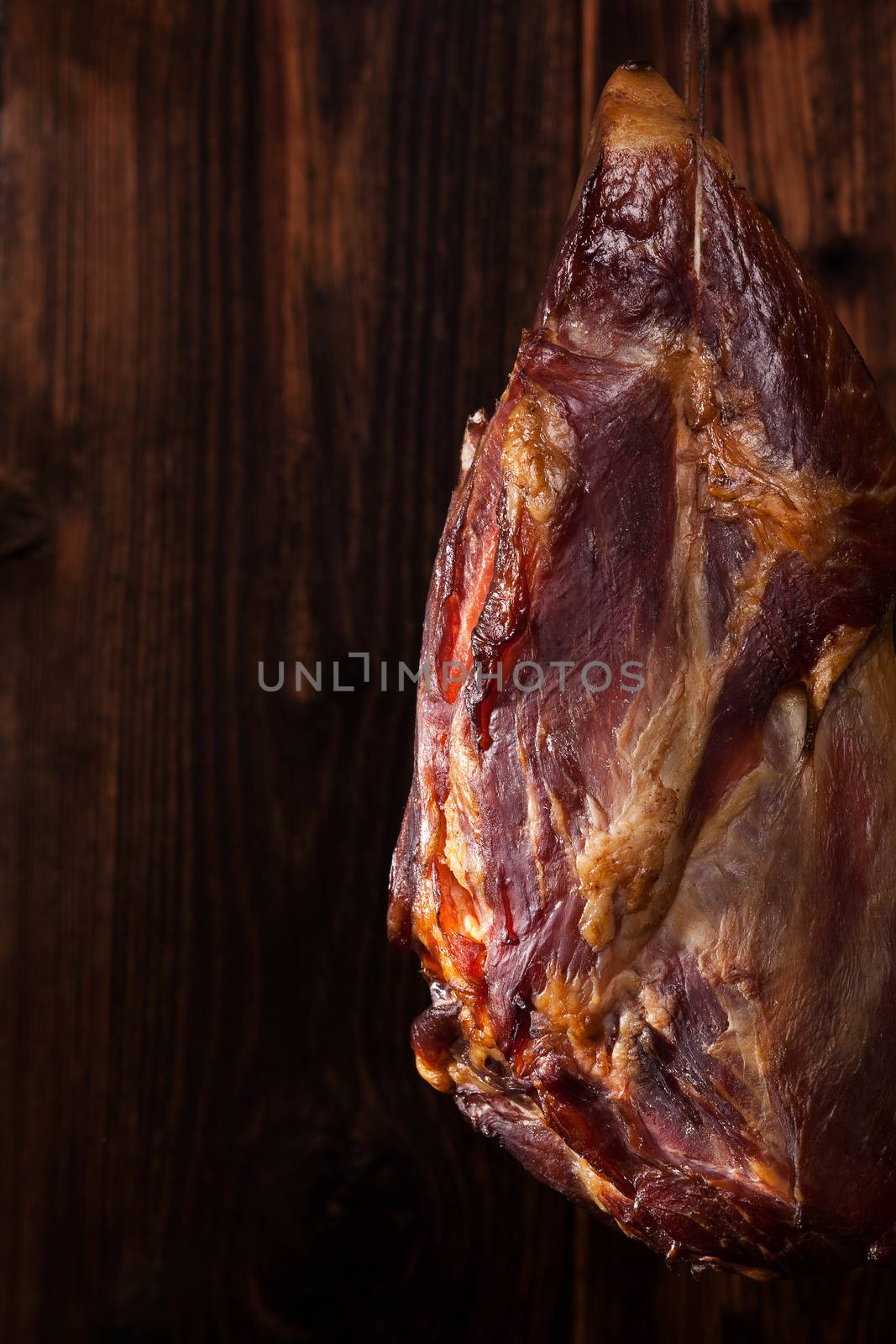 Traditional smoked meat hanging against wooden background. Culinary meat eating. 