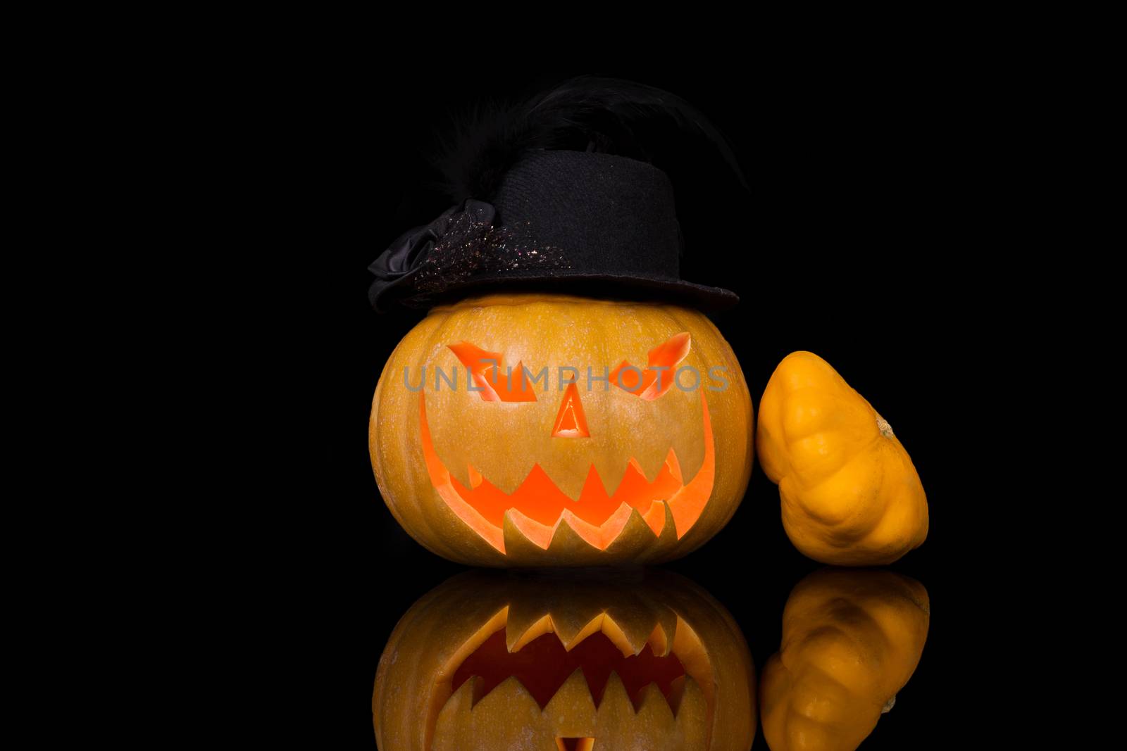 Creepy halloween pumpkin with hat isolated on black background. Traditional american halloween decoration.