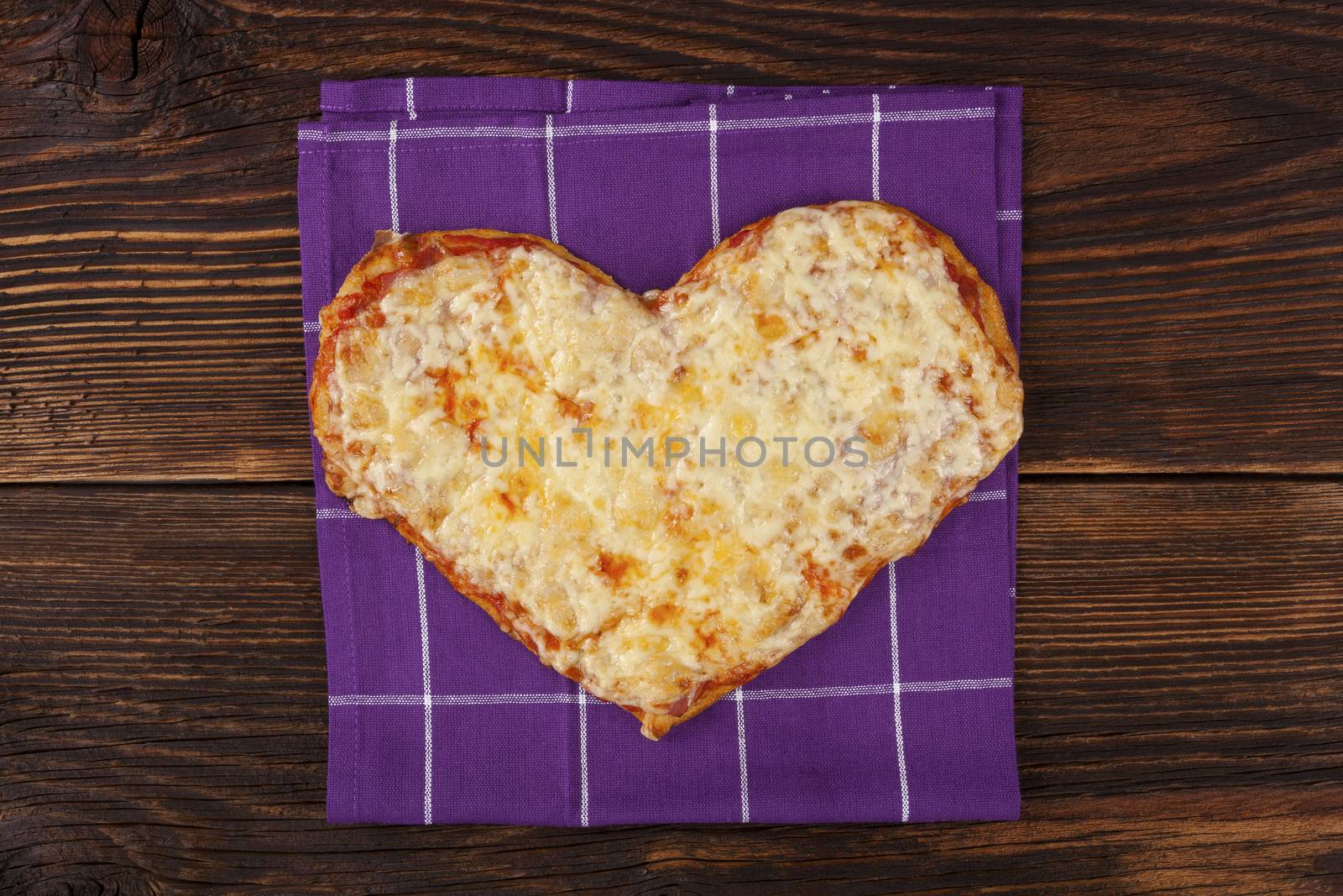 Delicious pizza in heart shape on wooden table, top view. Culinary pizza eating.