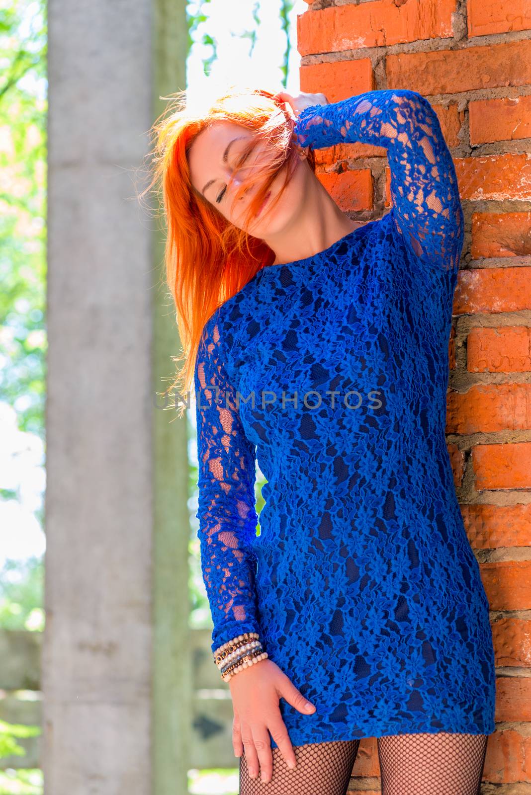 girl with red hair posing near brick wall