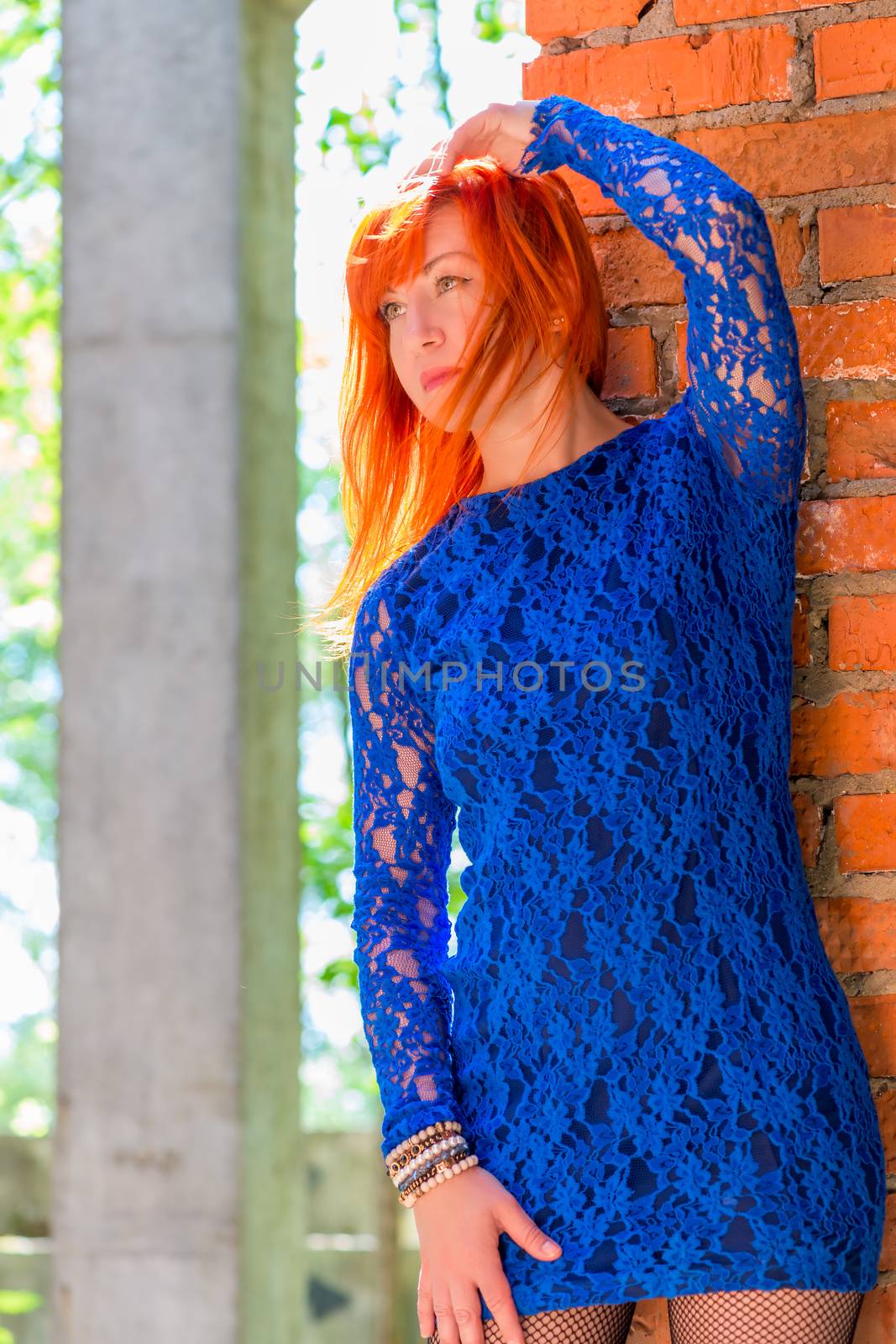 Girl 30 years in lace dress posing near the wal