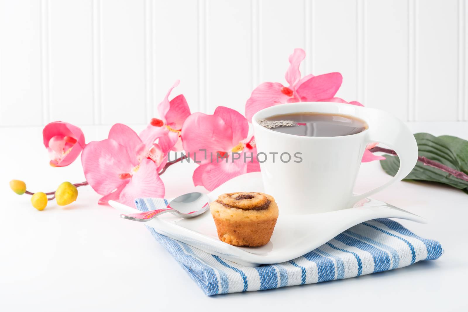 Small cinnamon roll served with a cup of hot tea.