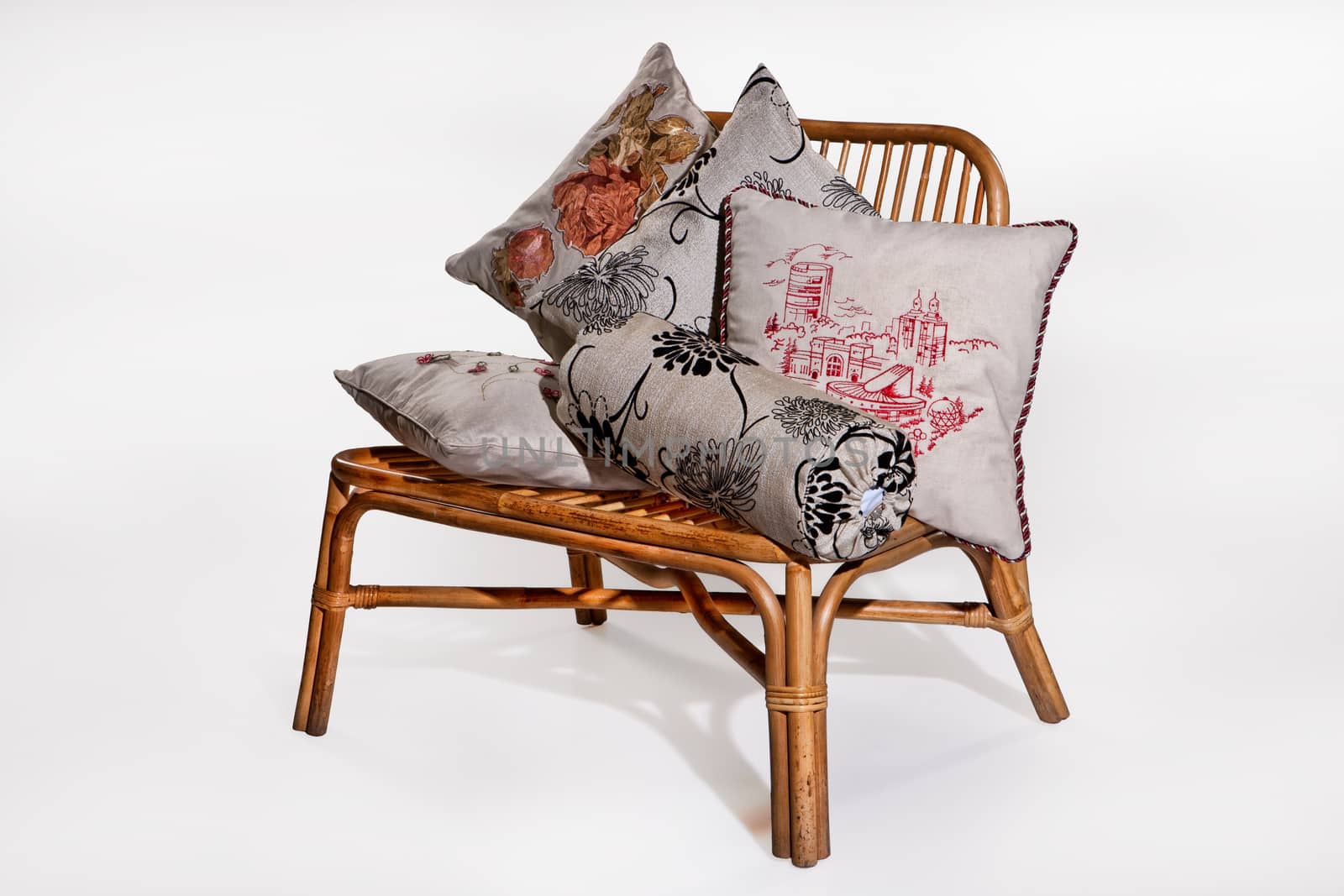 Decorative canvas pillows and wooden wicker bench on an isolated studio background