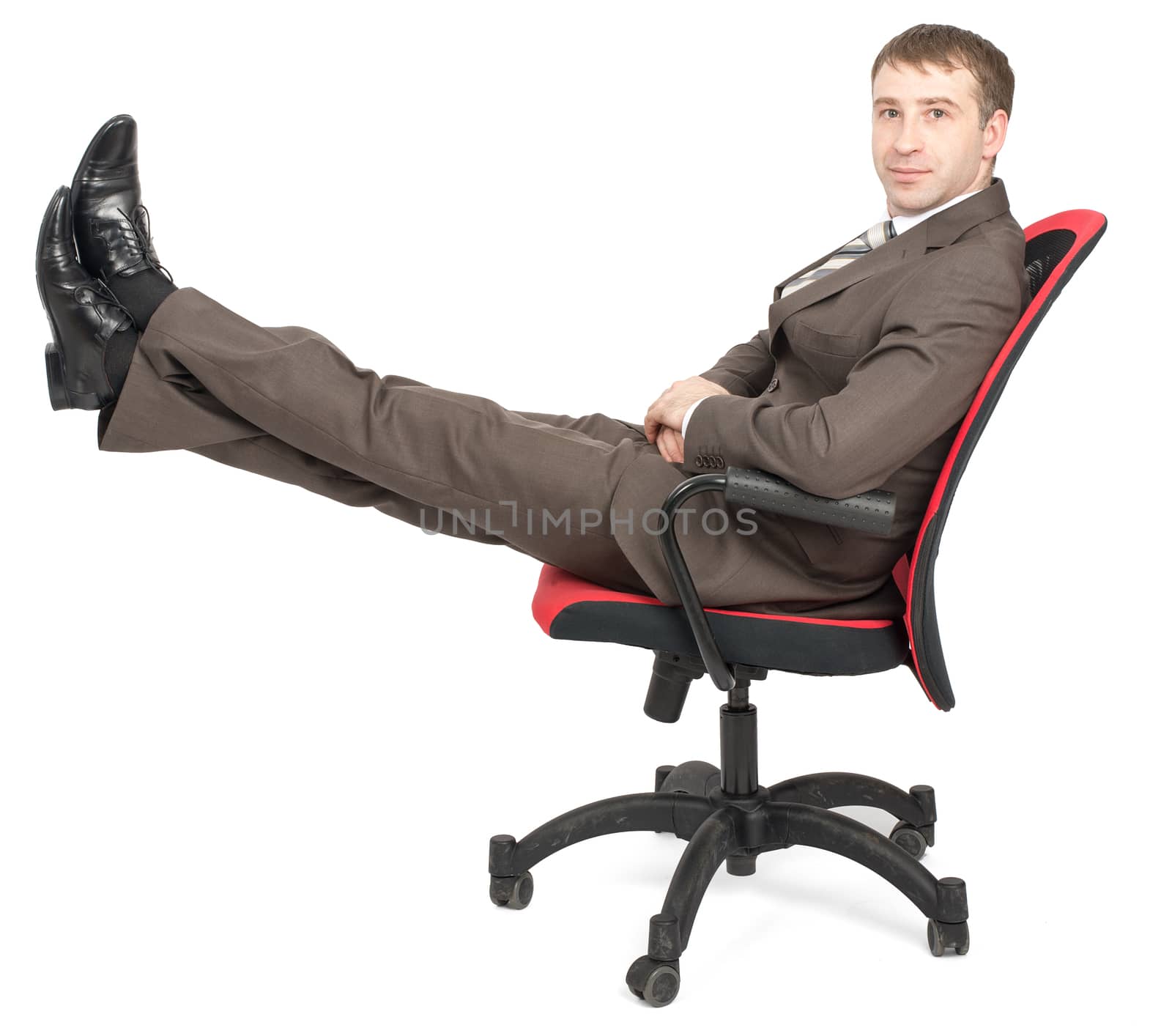 Businessman sitting on chair with legs up and looking at camera isolated on white background, side view