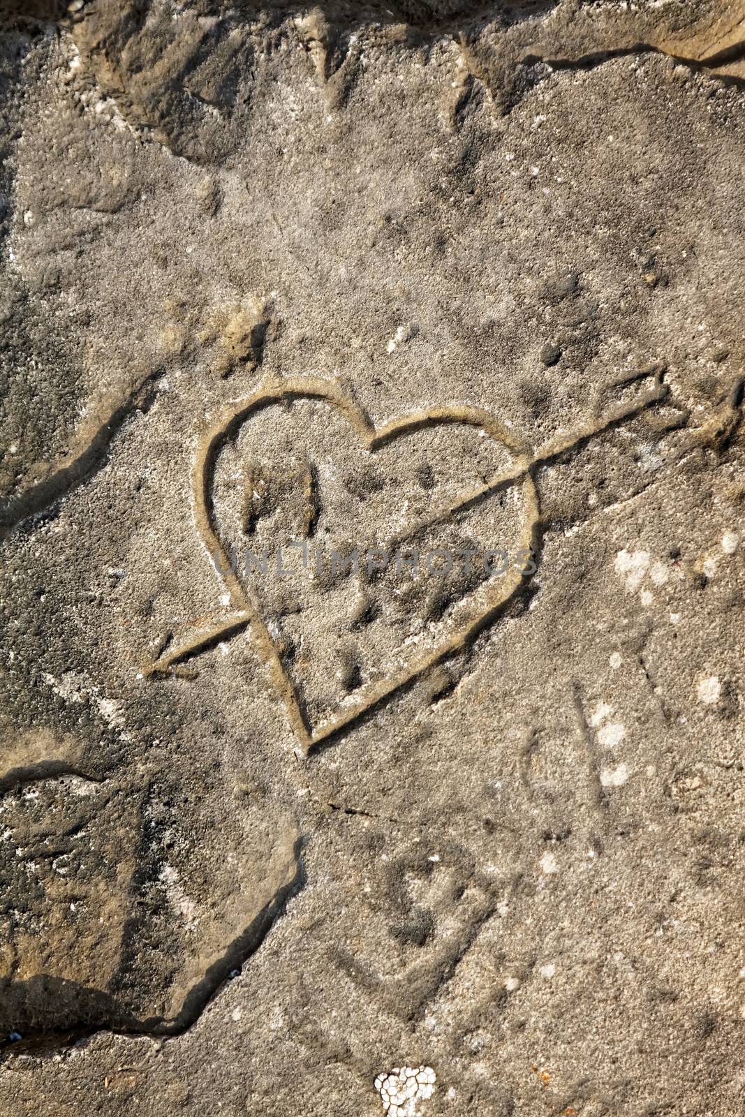 Heart and arrow engraved on rocky beach