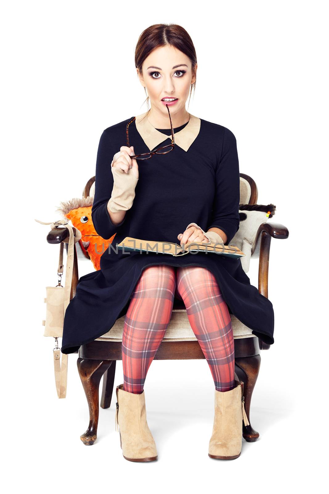 Studio shot of surprised girl holding an open book on her knees. 