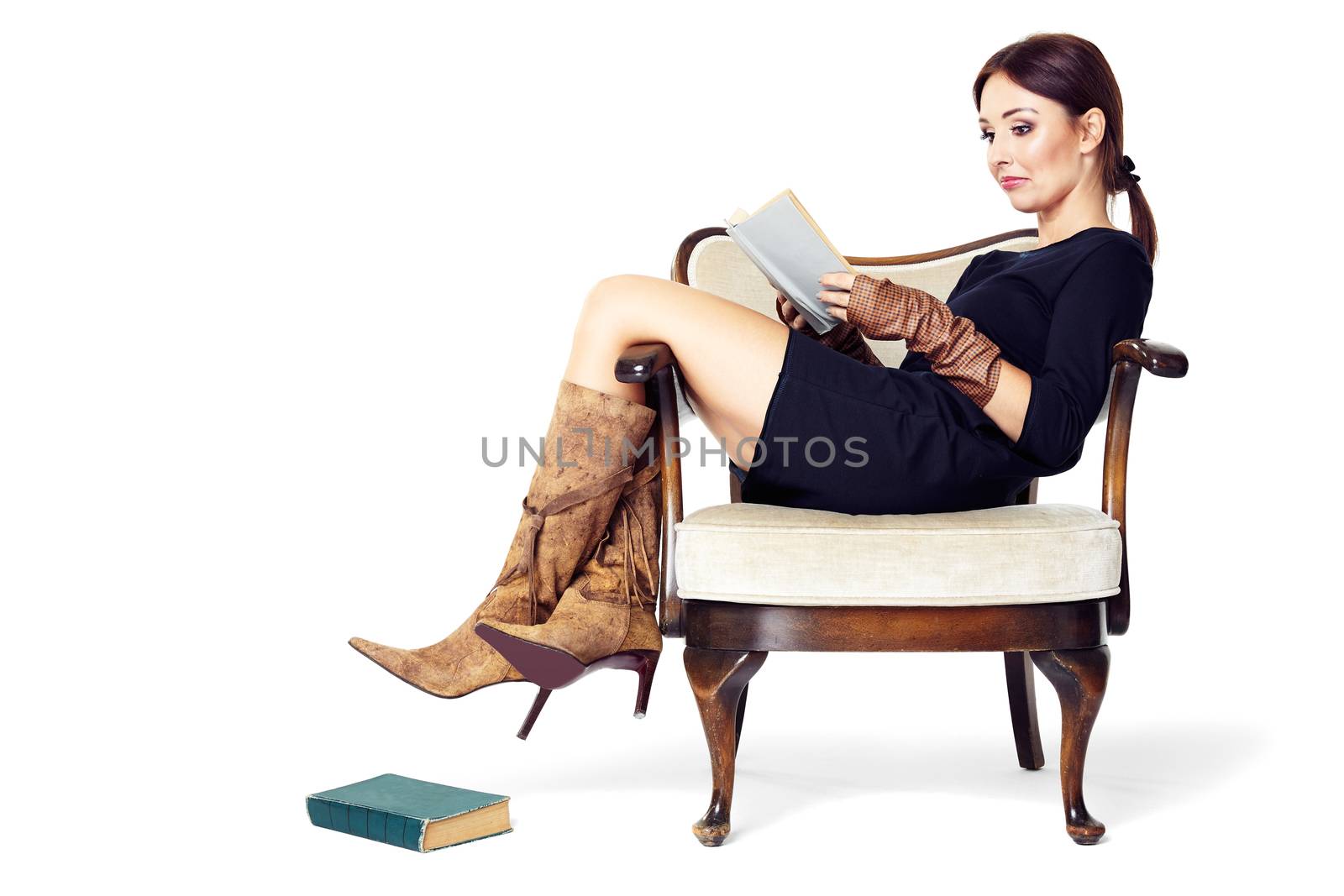 Attractive woman reading a book while sitting comfortably in an old chair.