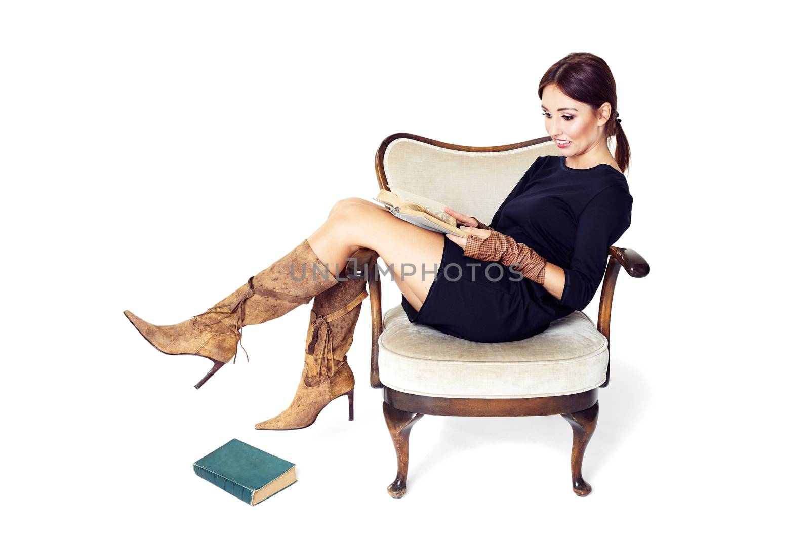 Attractive woman reading a book while sitting comfortably in an old chair.