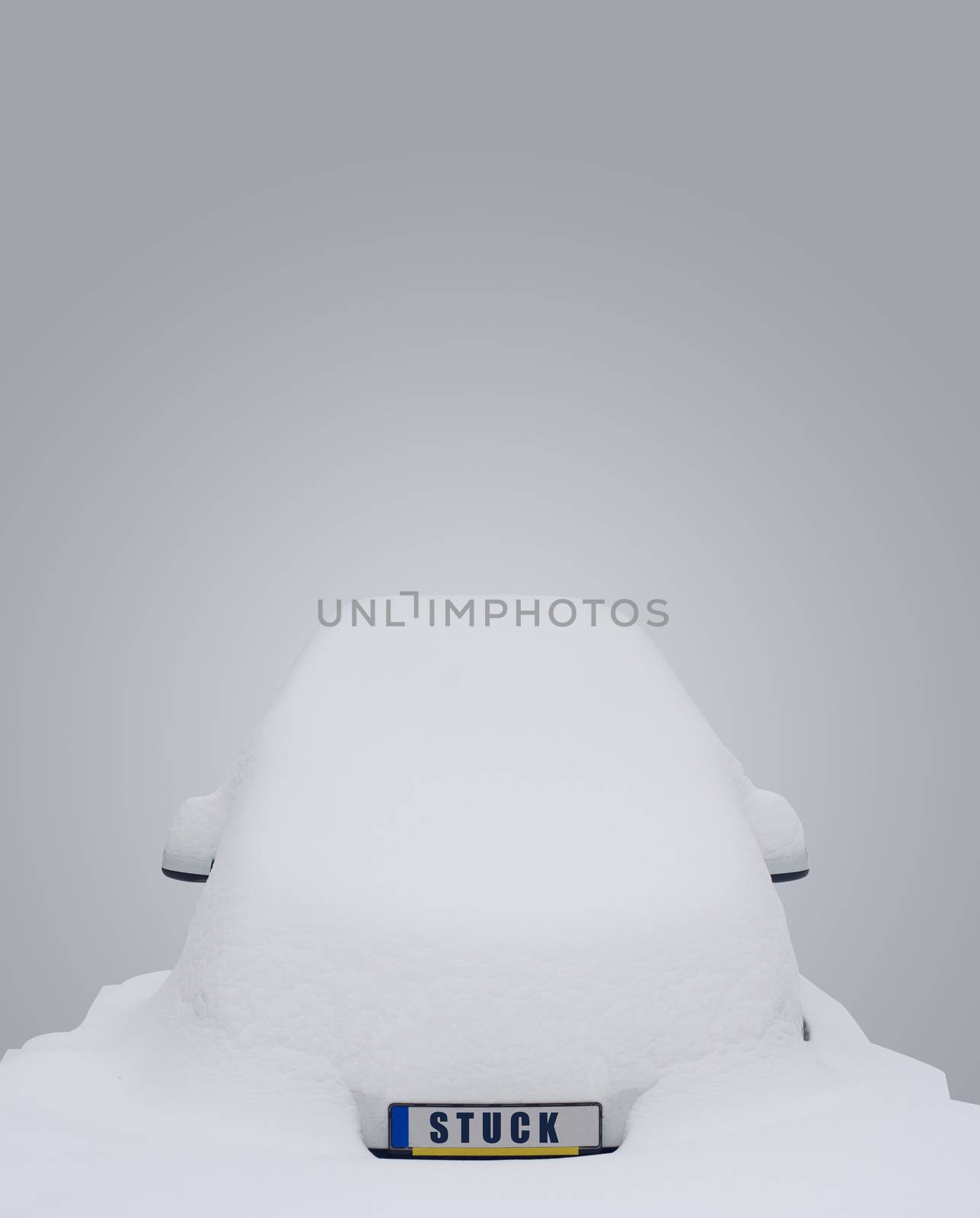 Car covered in snow with the word stuck writen on the license plate on grey background 