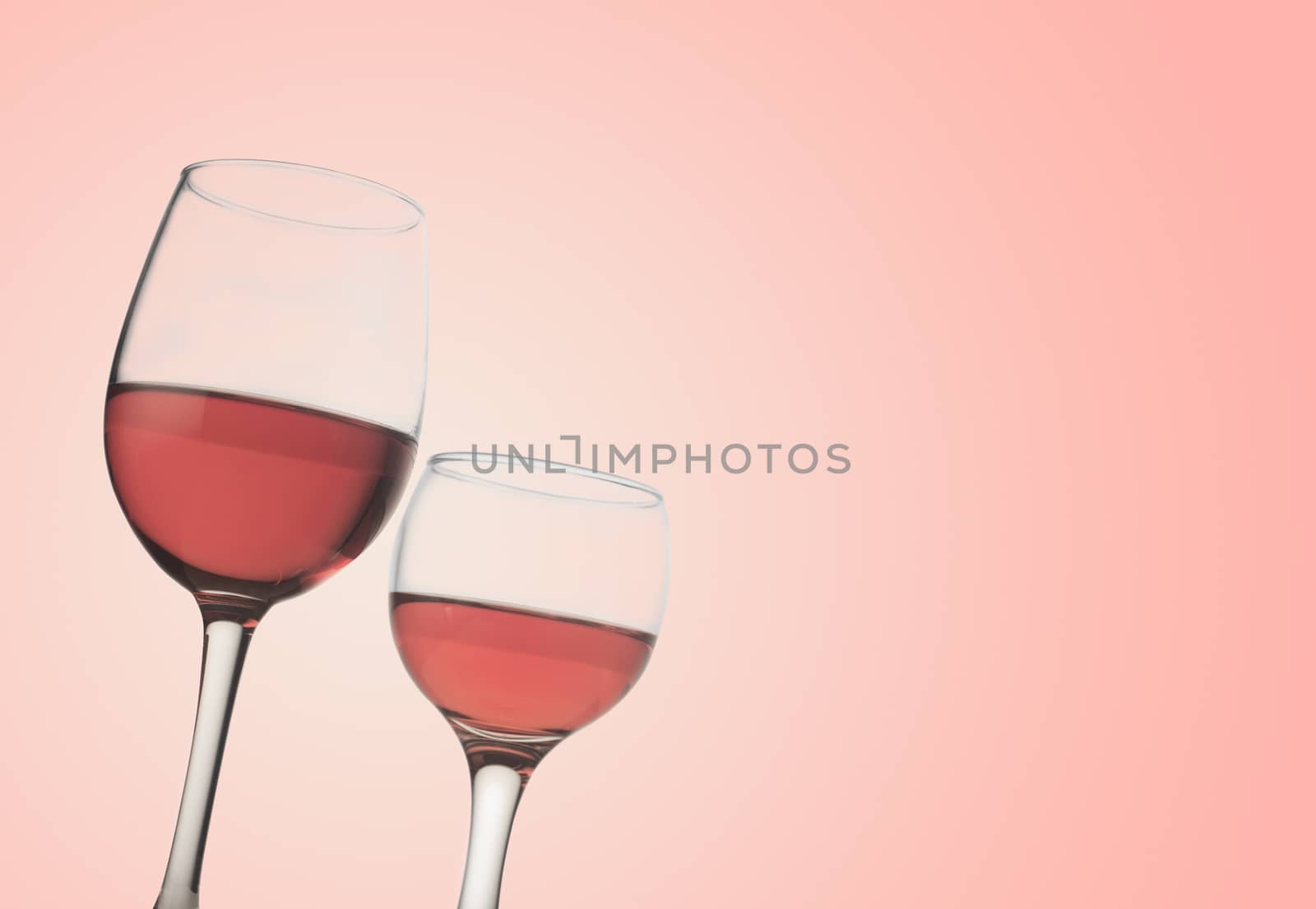 Horizontal front view of two rose wine glasses isolated on pink background