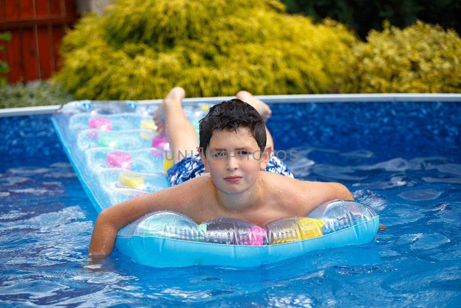 Happy young boy with inflatable water lounger in the swimming pool