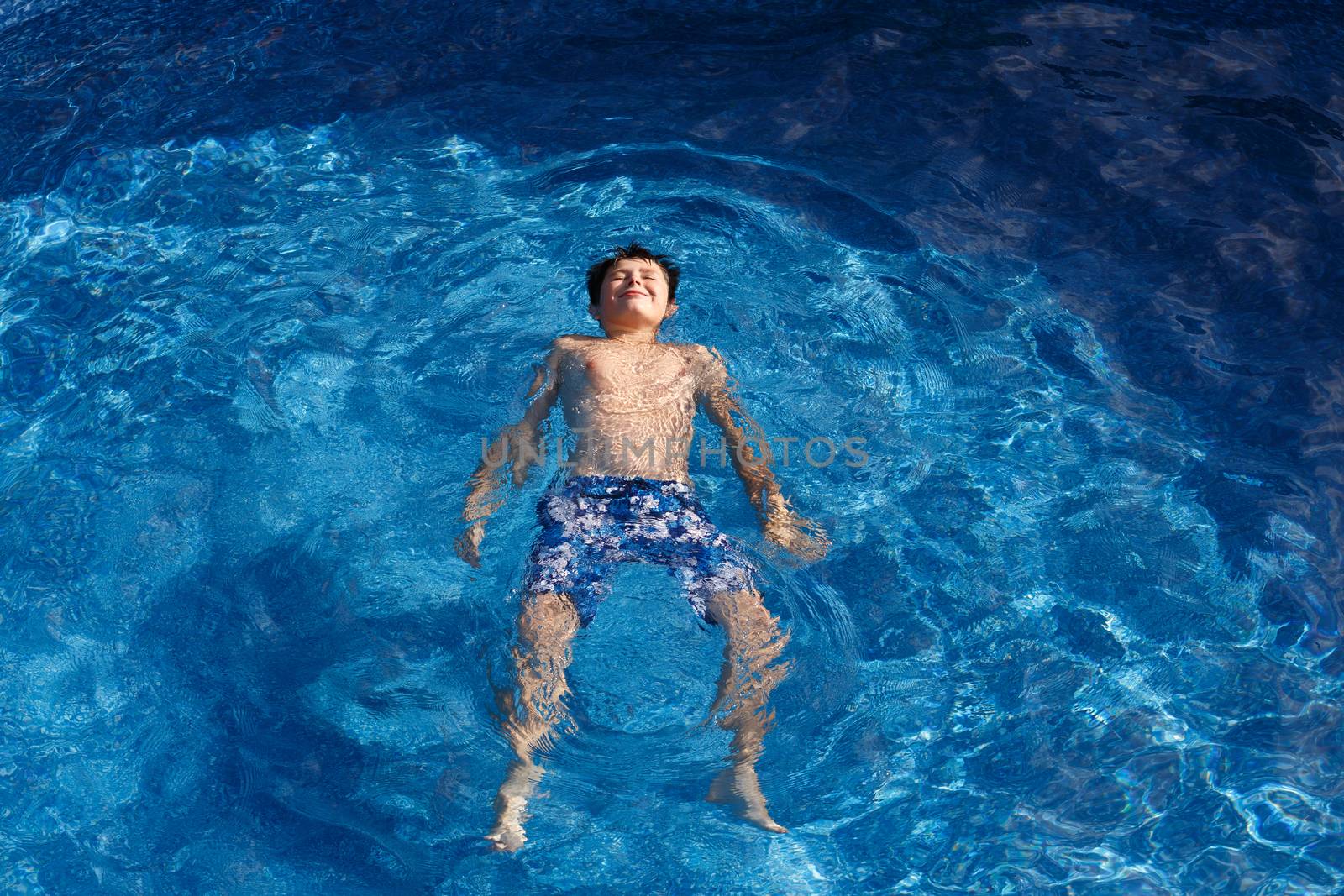 Young teenager boy in the garden swimming pool