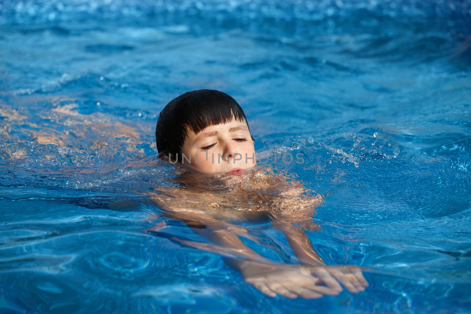 Young teenager boy in the garden swimming pool