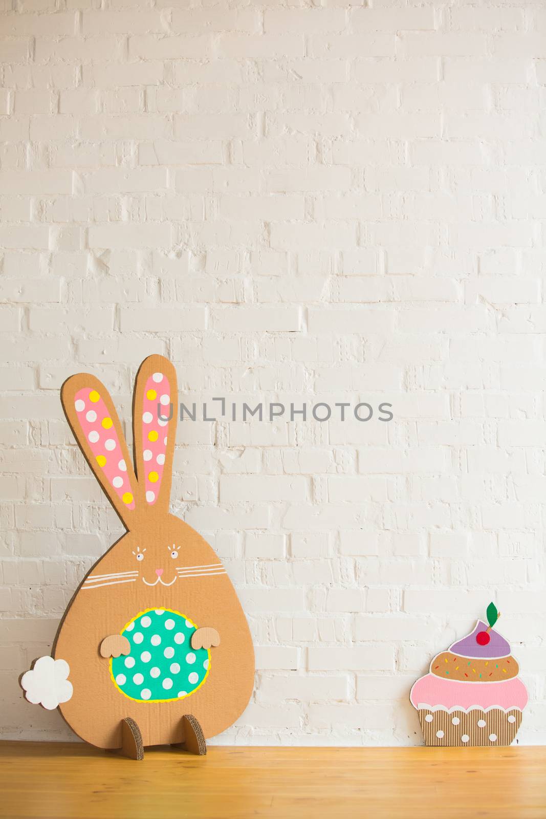 Decoration for Easter. Rabbit of cardboard on a white brick wall