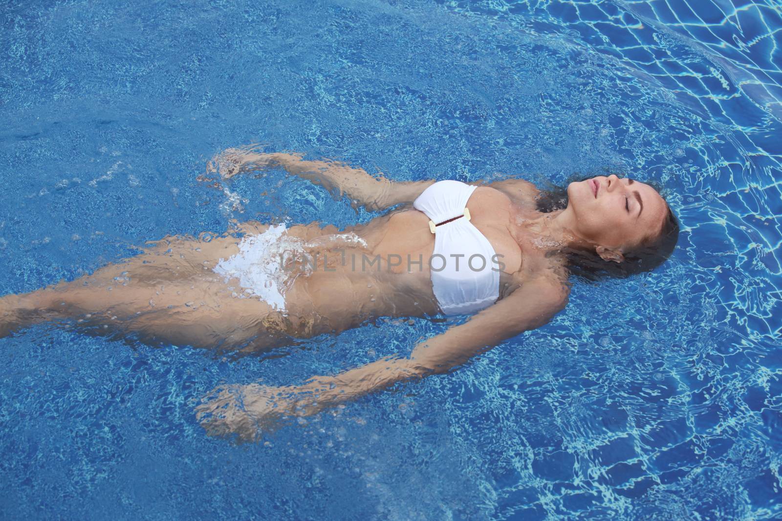 Close up view of an attractive young woman floating in swimming pool
