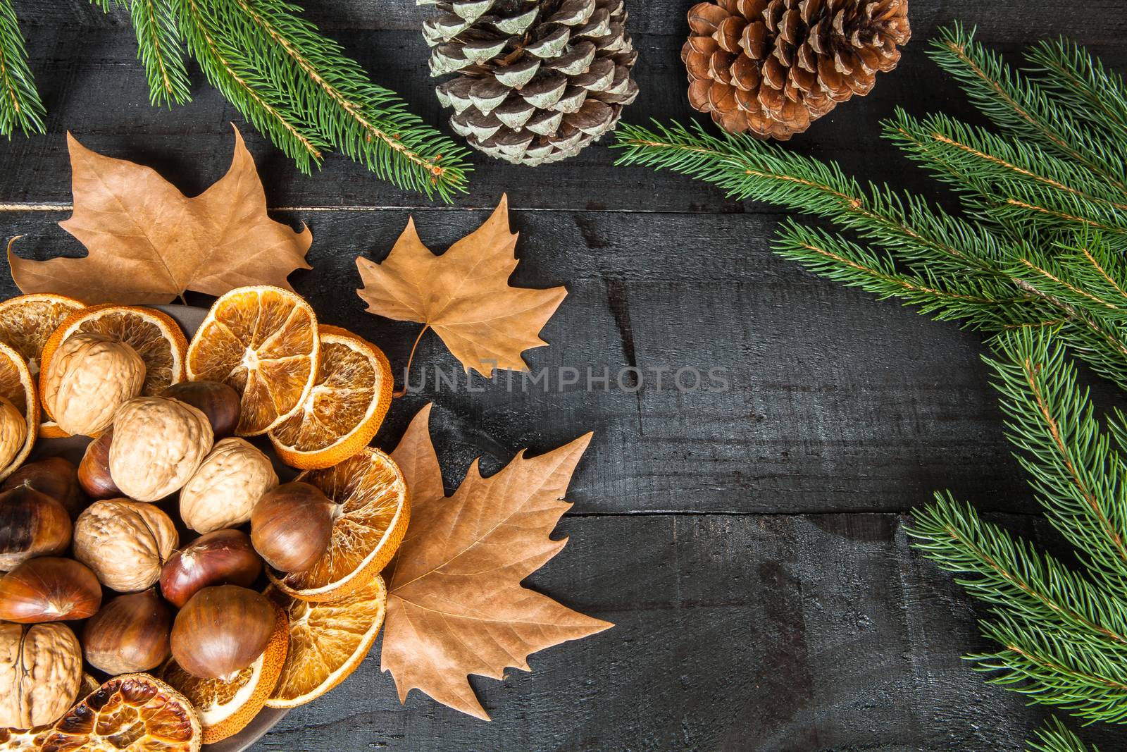 Composition of cutlery on wood background for branches and a decorative nuts, dry oranges, pain fruit and leafs for informal dinners or family celebrations in autumn winter season