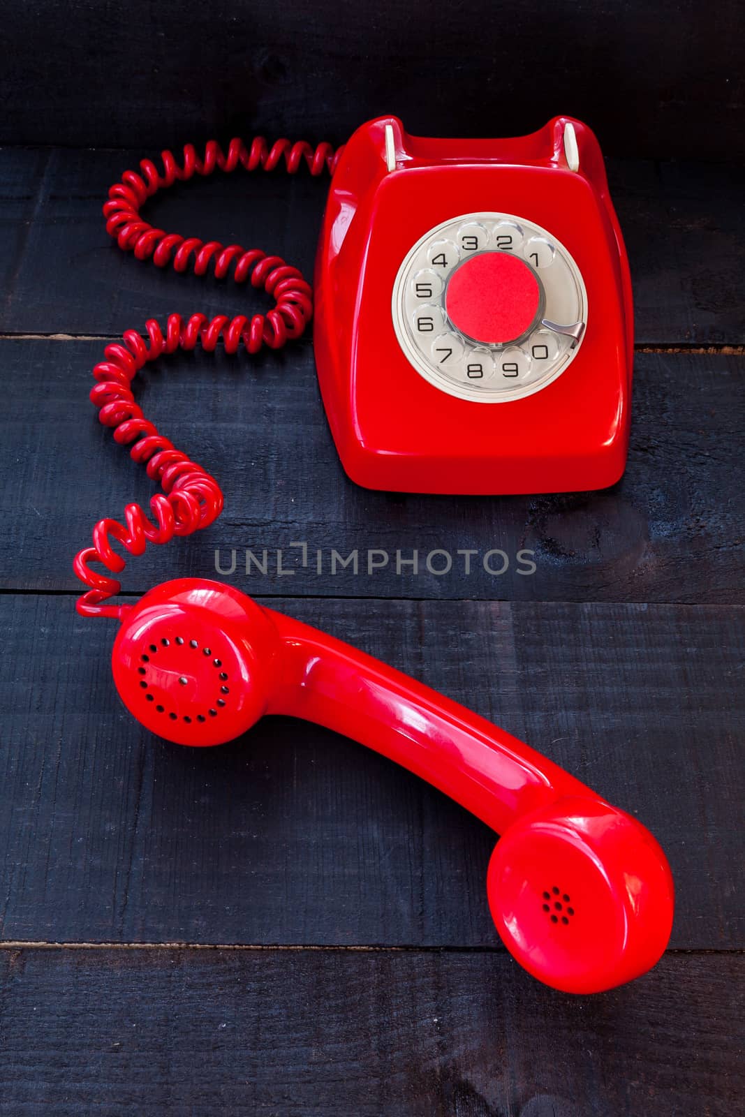 The image represents a vintage red phone on a dark wood background conceptualizing communication or lack thereof