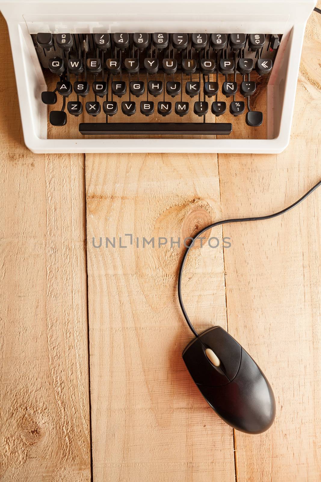 The image shows an antique typewriter connected to a computer mouse imitating a laptop and conceptualizing the obsolescence of technology