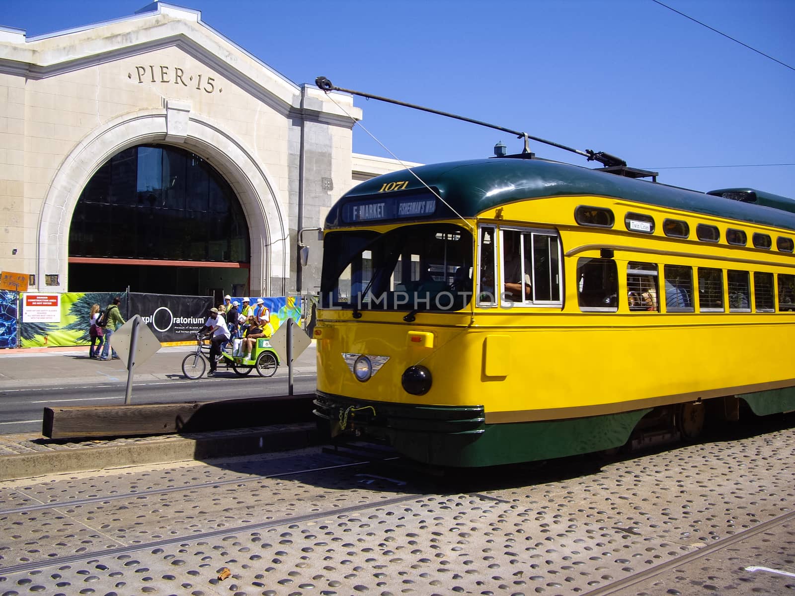Yellow Tram and three wheeled bike at Pier 15 in San Francisco,  by emattil