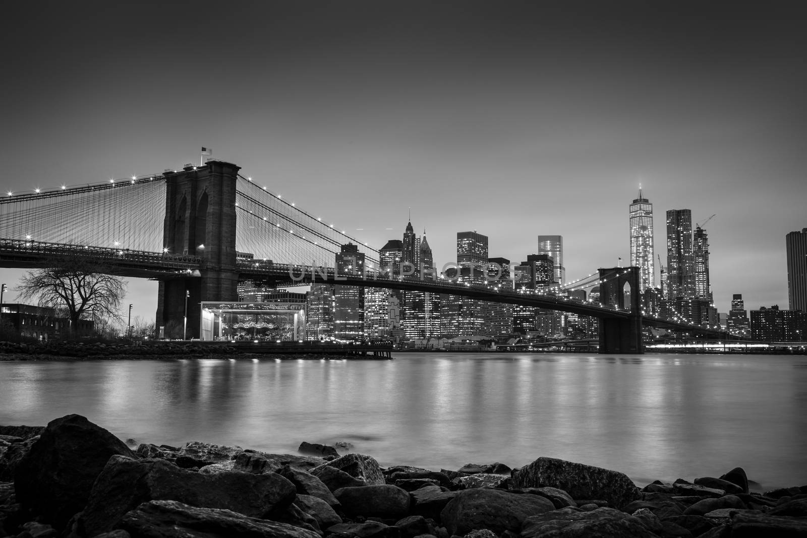 Brooklyn bridge and New York City Manhattan downtown skyline at dusk with skyscrapers illuminated over East River panorama. Copy space. Black and white image.