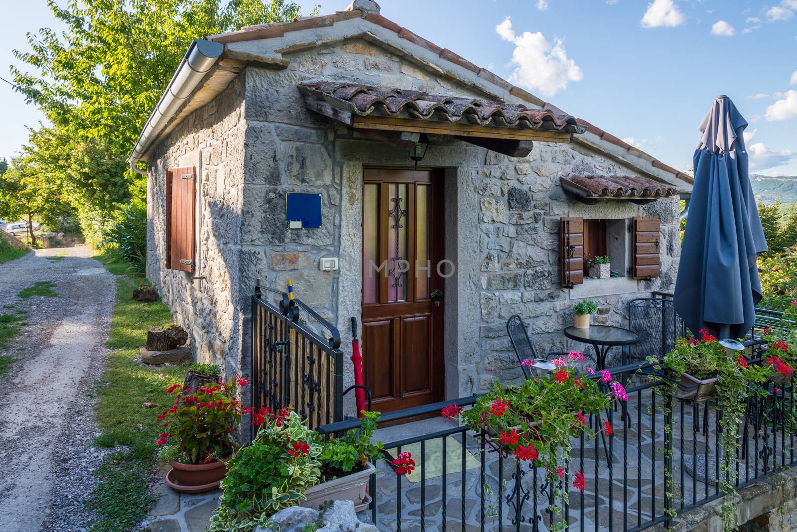 small stone house with a metal fence by vlaru