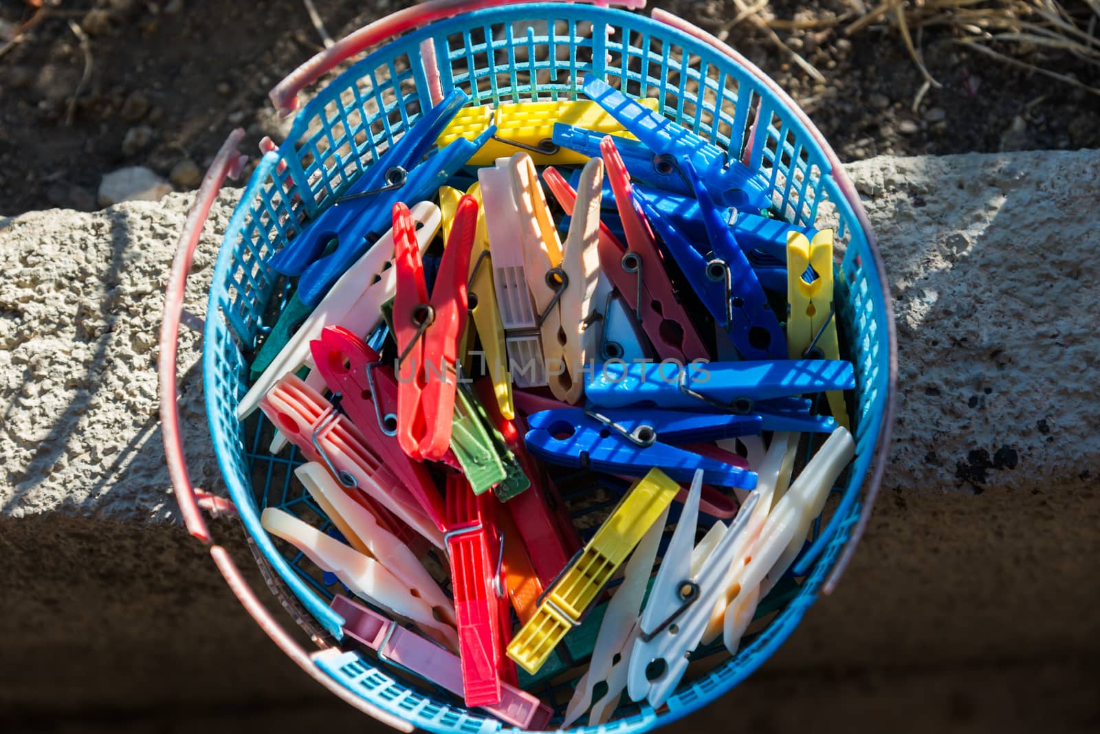 colored plastic clothespins in a basket by vlaru