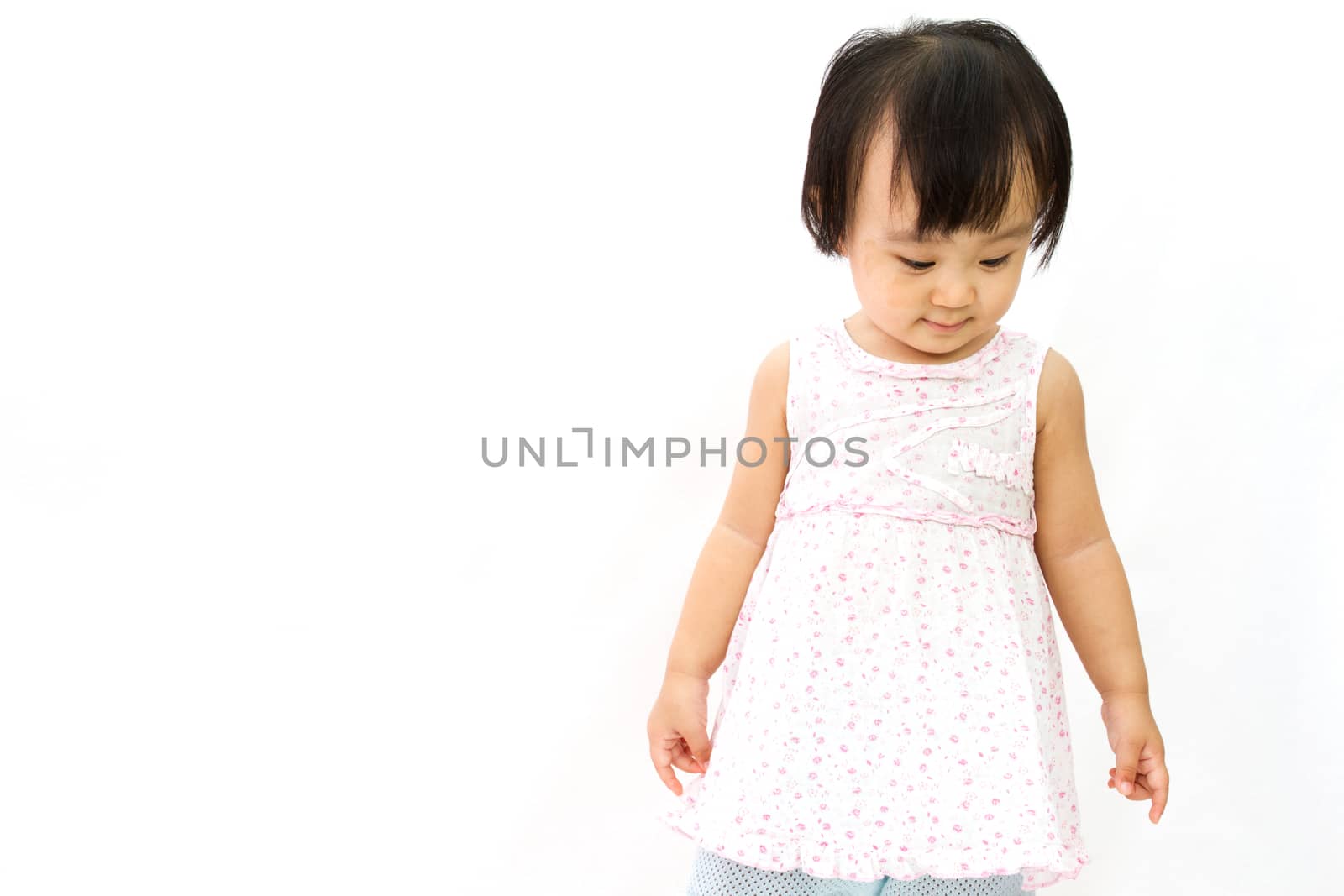 Chinese Little Girl looks down for a portrait in studio on plain white isolated background.
