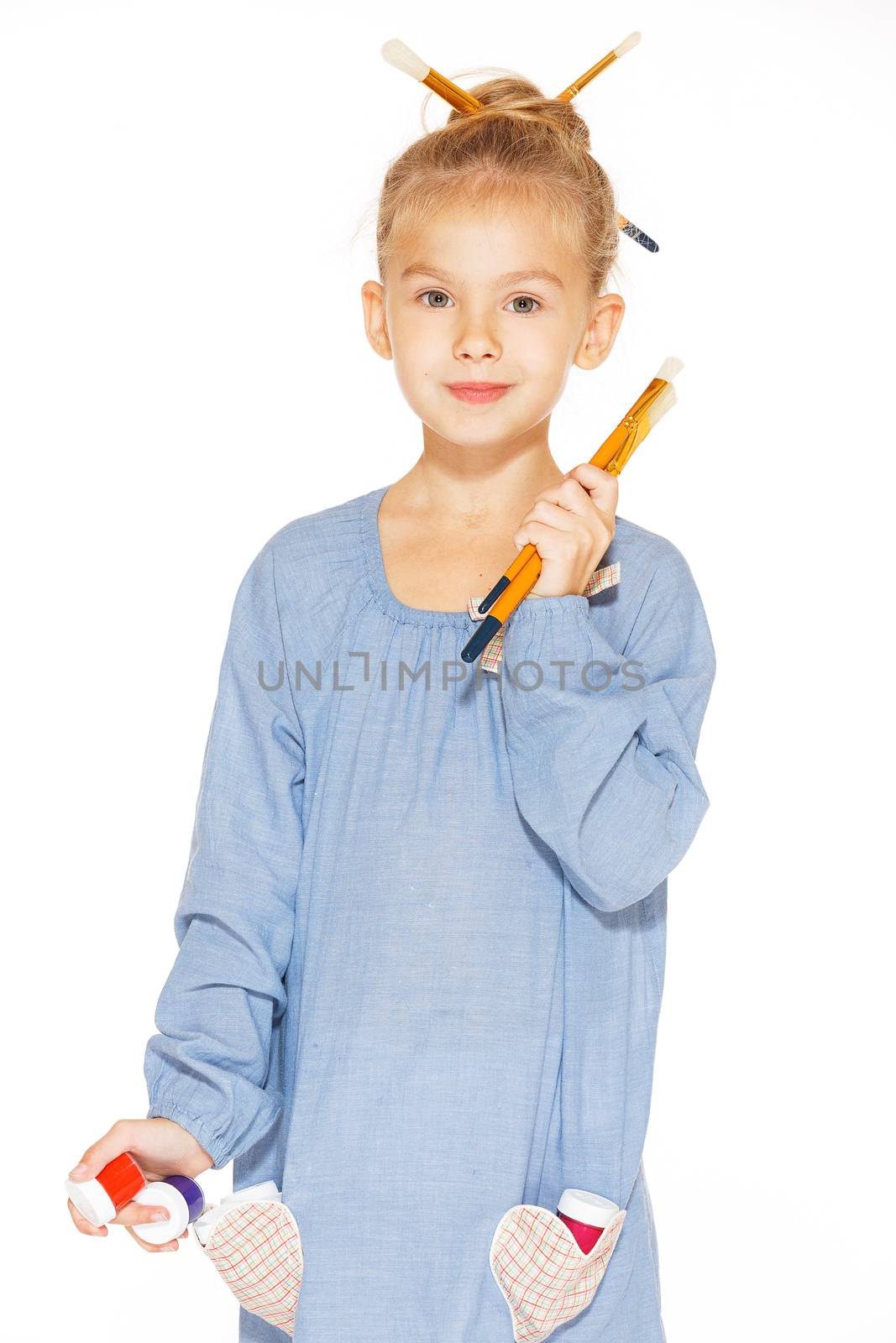Little girl painter in a blue dress with paints and brushes