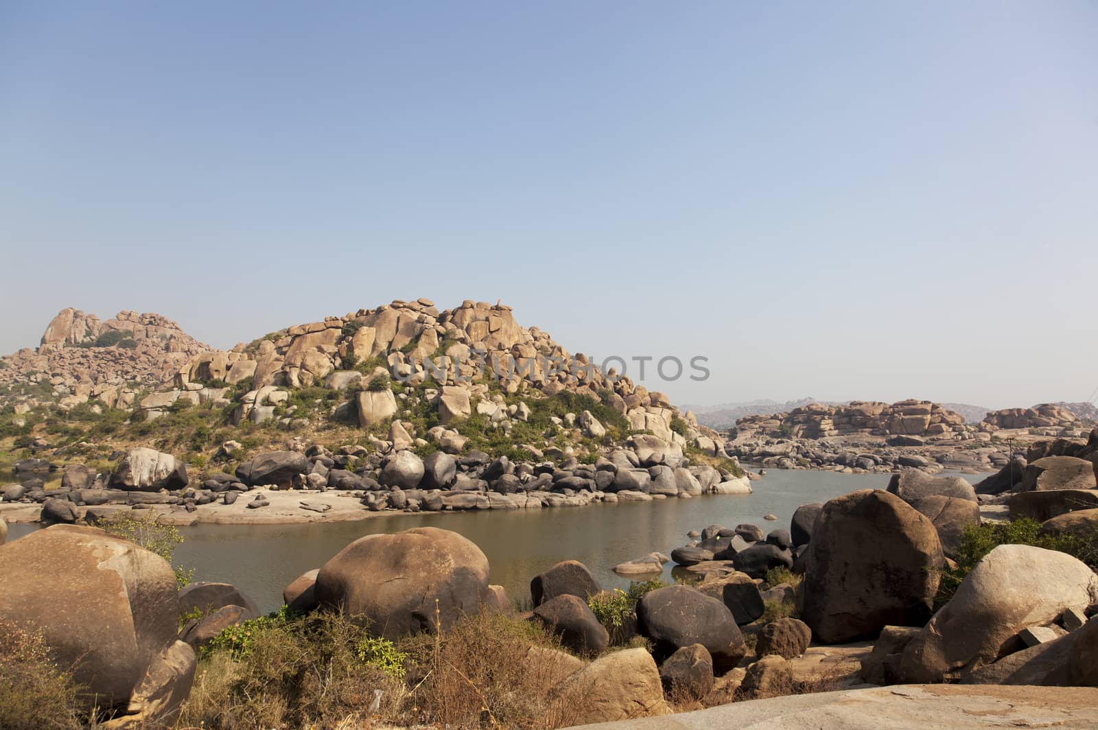 Hill with amazing stones and river at Hampi temple complex in India
