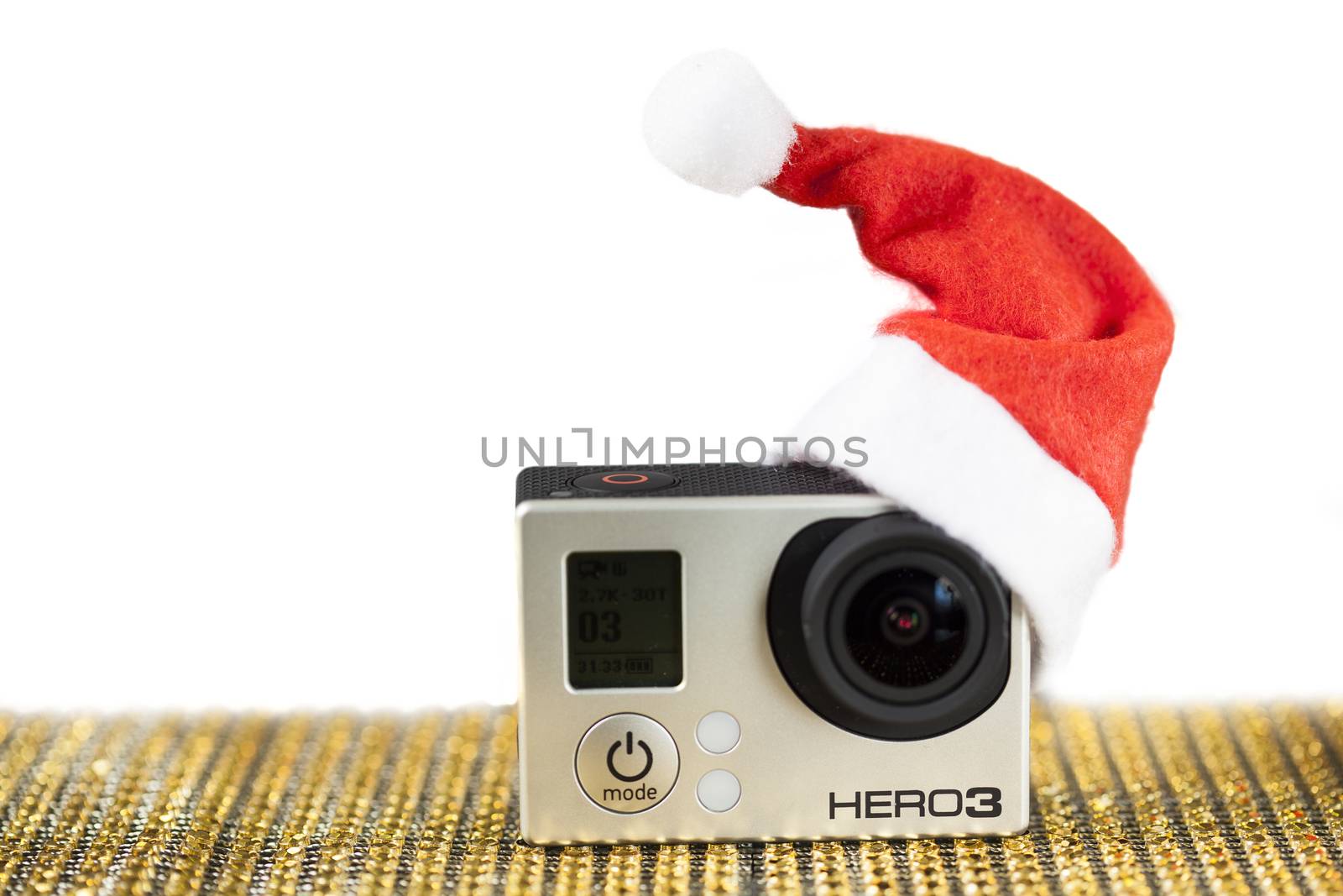 GoPro Hero 3 on golden pattern surface with a santa hat.
