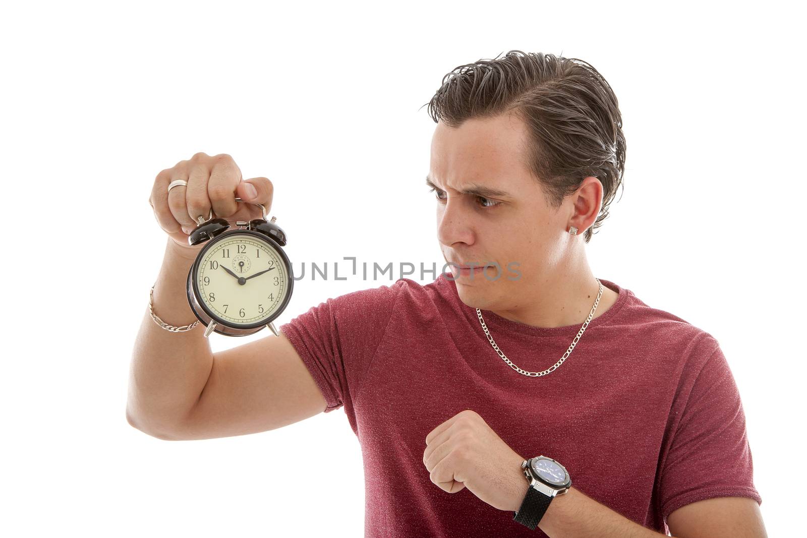 Young man is angry at alarm clock over white background