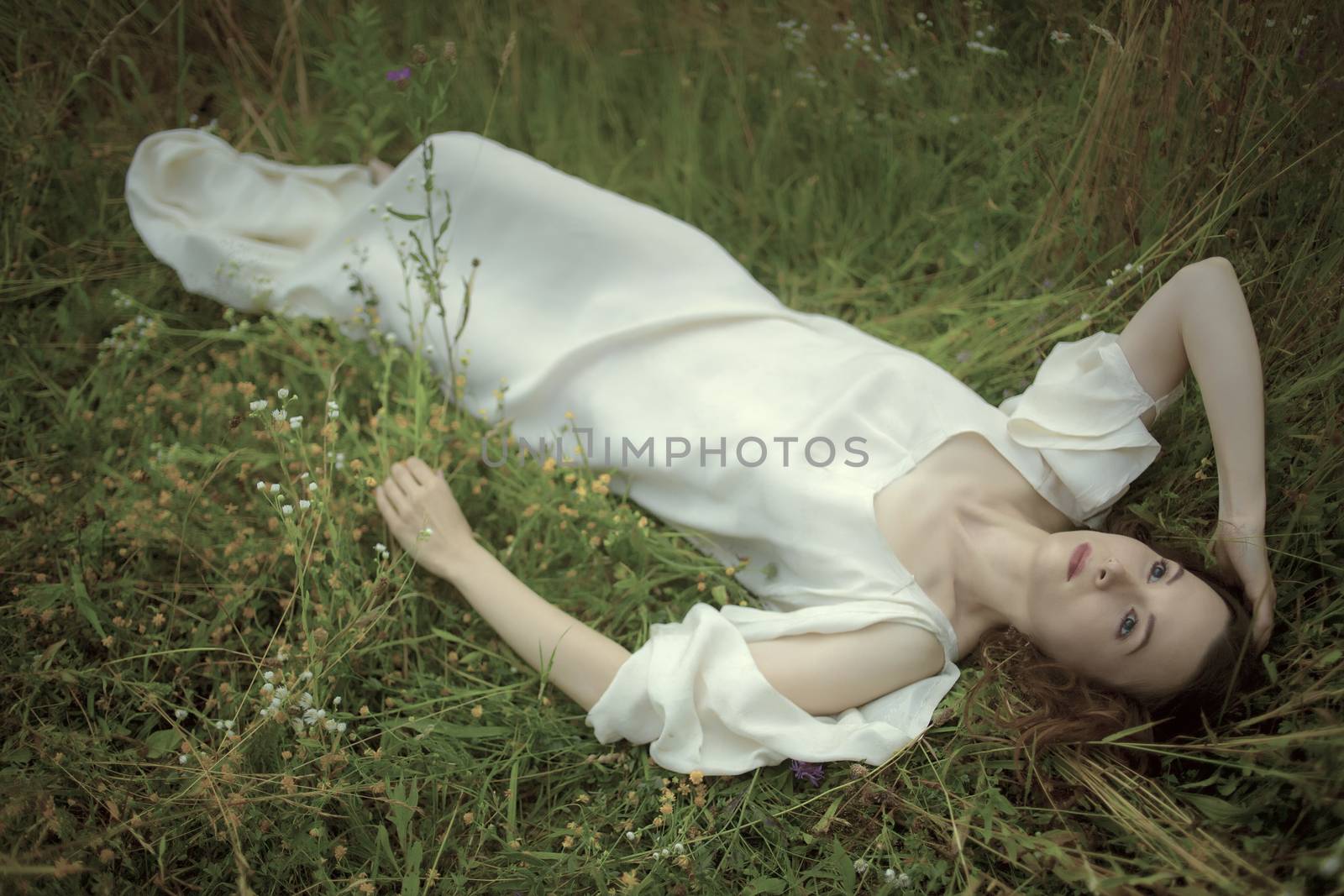 Dreamy girl lying in grass.Hommage to Pre-Raphaelities painters.