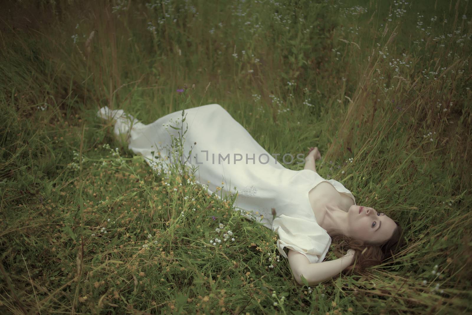 Dreamy girl lying in grass.Hommage to Pre-Raphaelities painters.