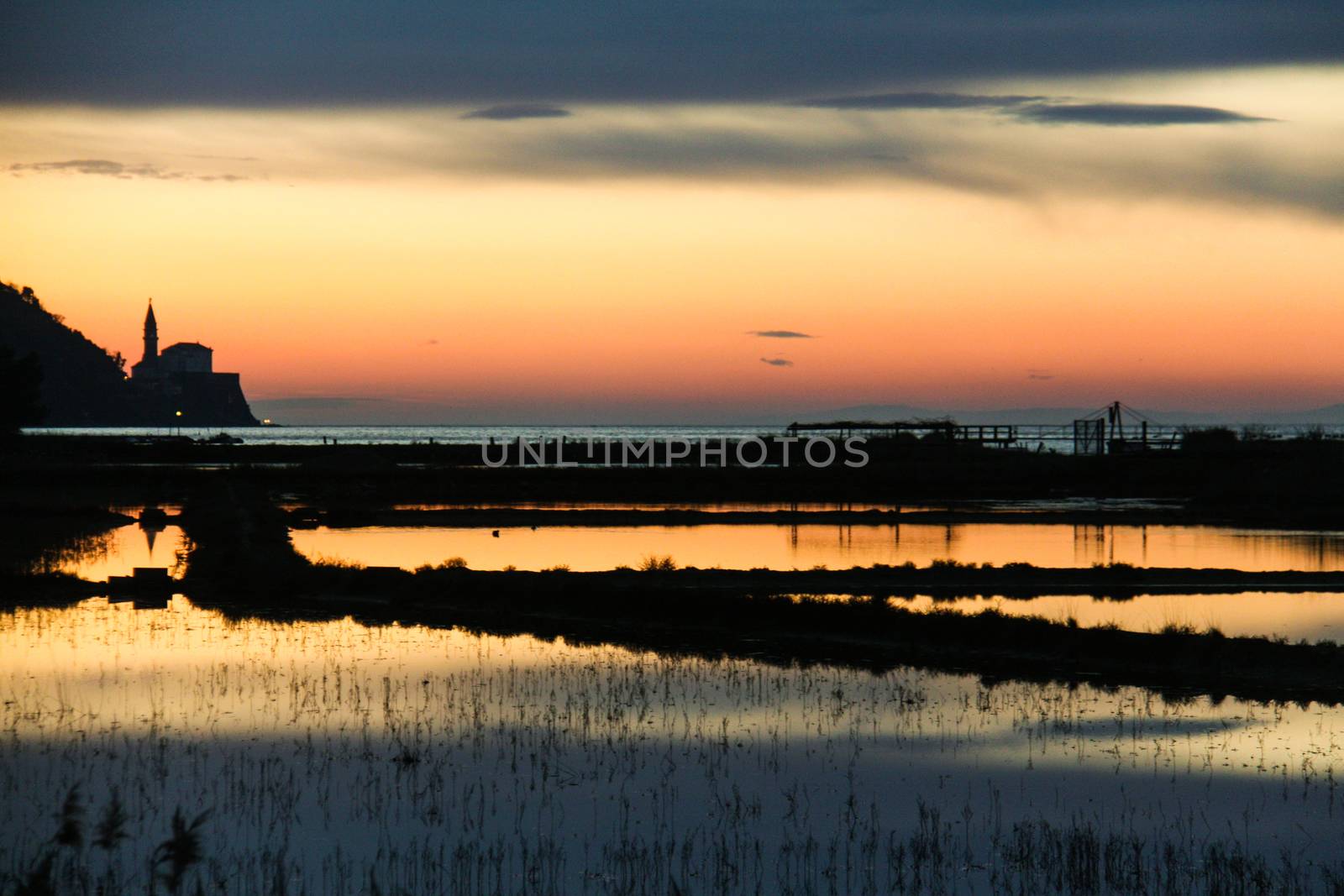 Sunset on saltpans with a church in the back (in Strunjan/Piran, Slovenia)