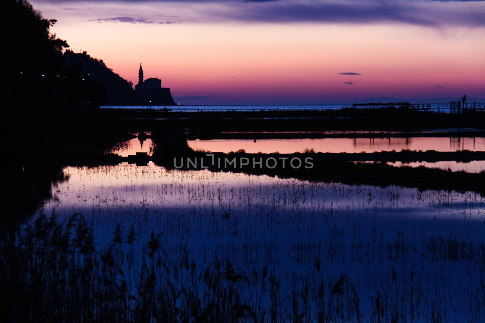 Sunset on saltpans with a church in the back (in Strunjan/Piran, Slovenia)