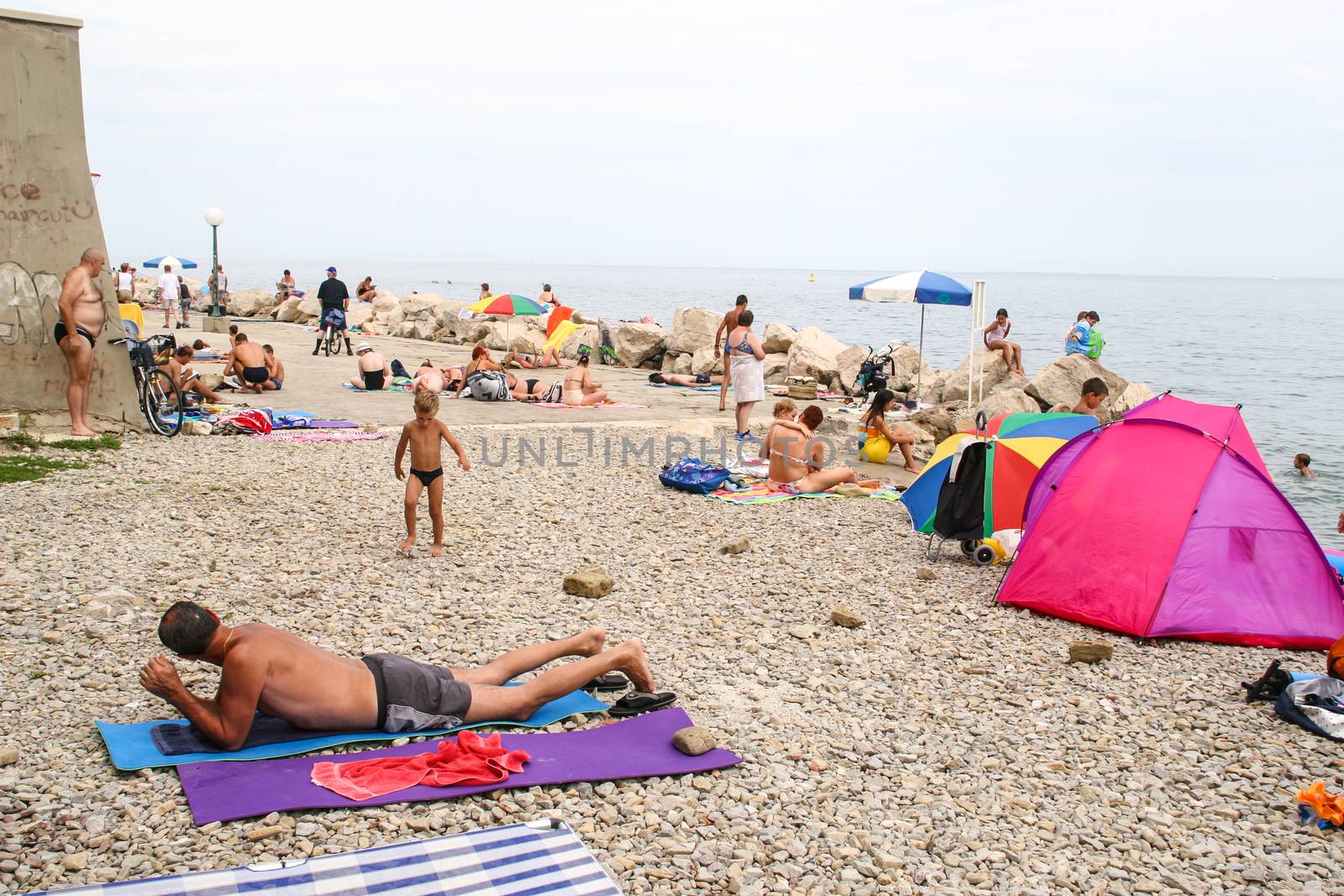 Piran, Slovenia - 9 August 2006: People at a beach on Slovenian coast. by Aarstudio