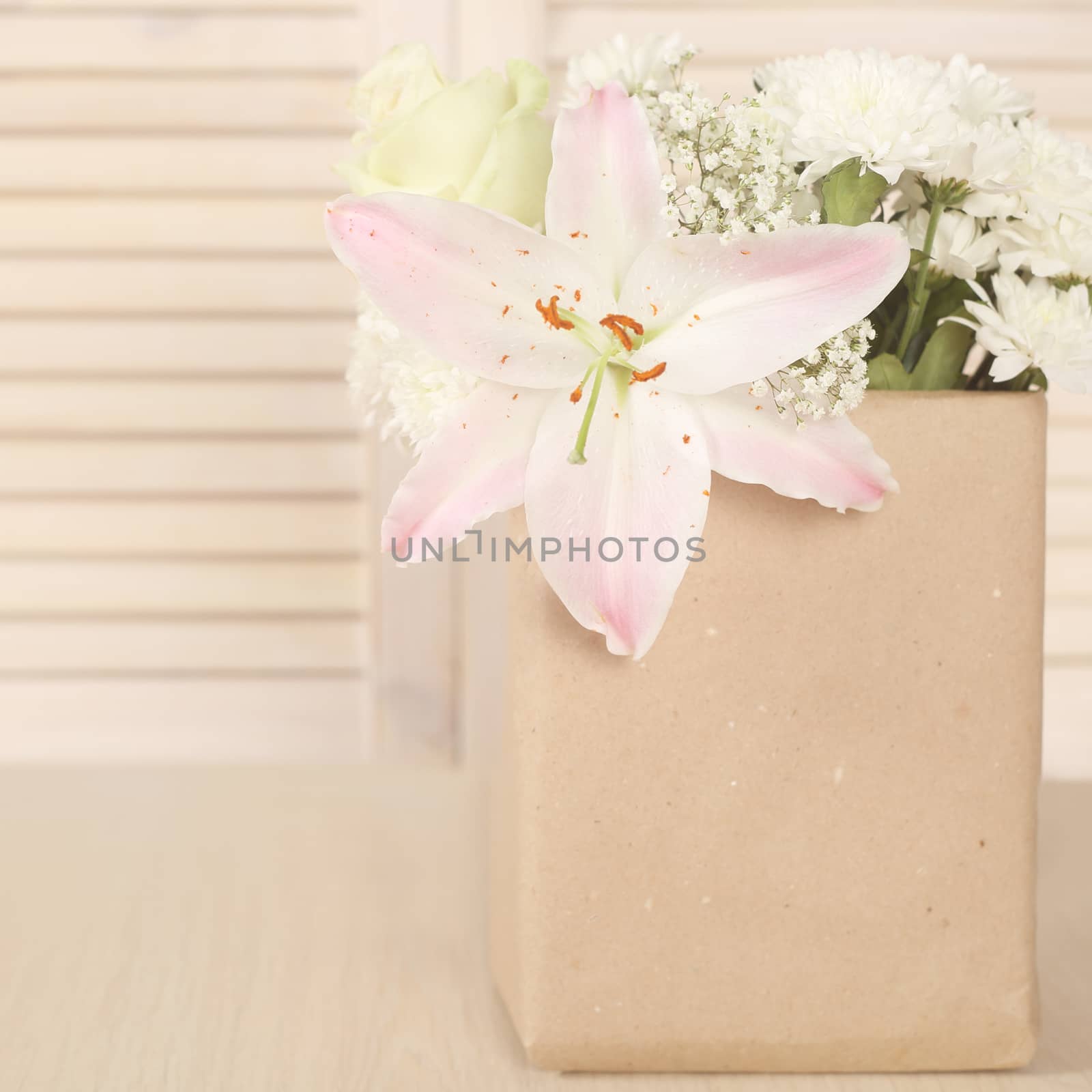 Flowers in brown paper bag on wooden background